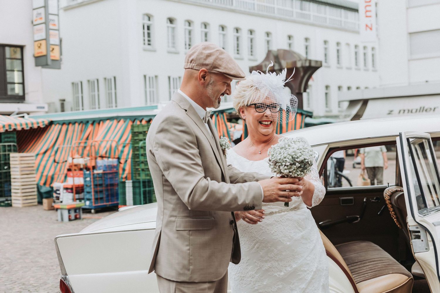 A happy couple exits their wedding ceremony while guests shower them with confetti on a city street.