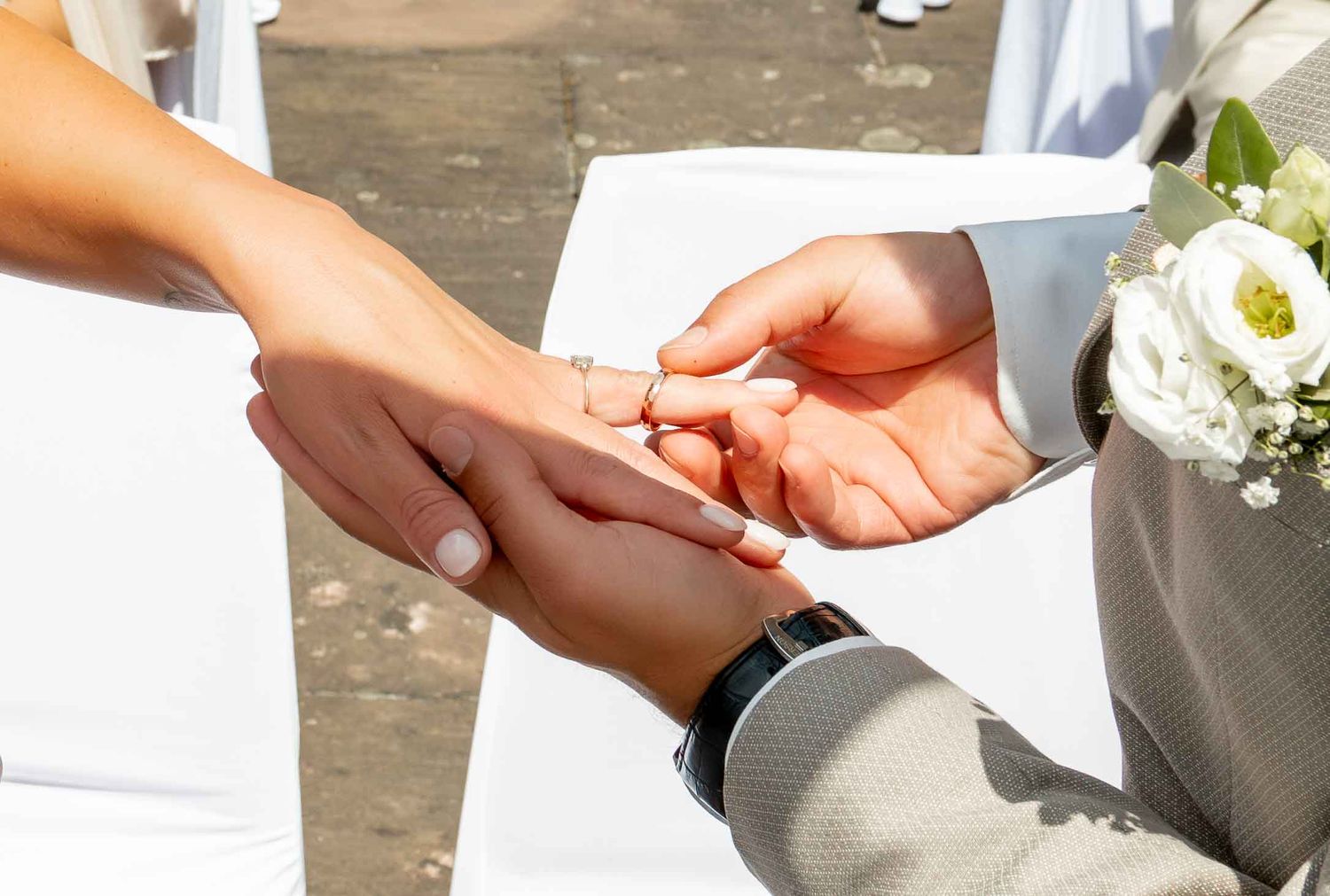 Close-up of hands exchanging wedding rings during ceremony.