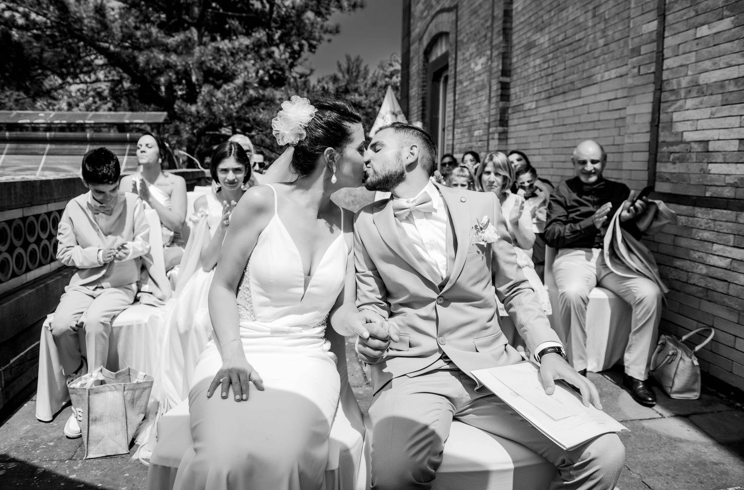 A sequence of black and white candid wedding photos showing guests laughing and reacting during an outdoor ceremony.