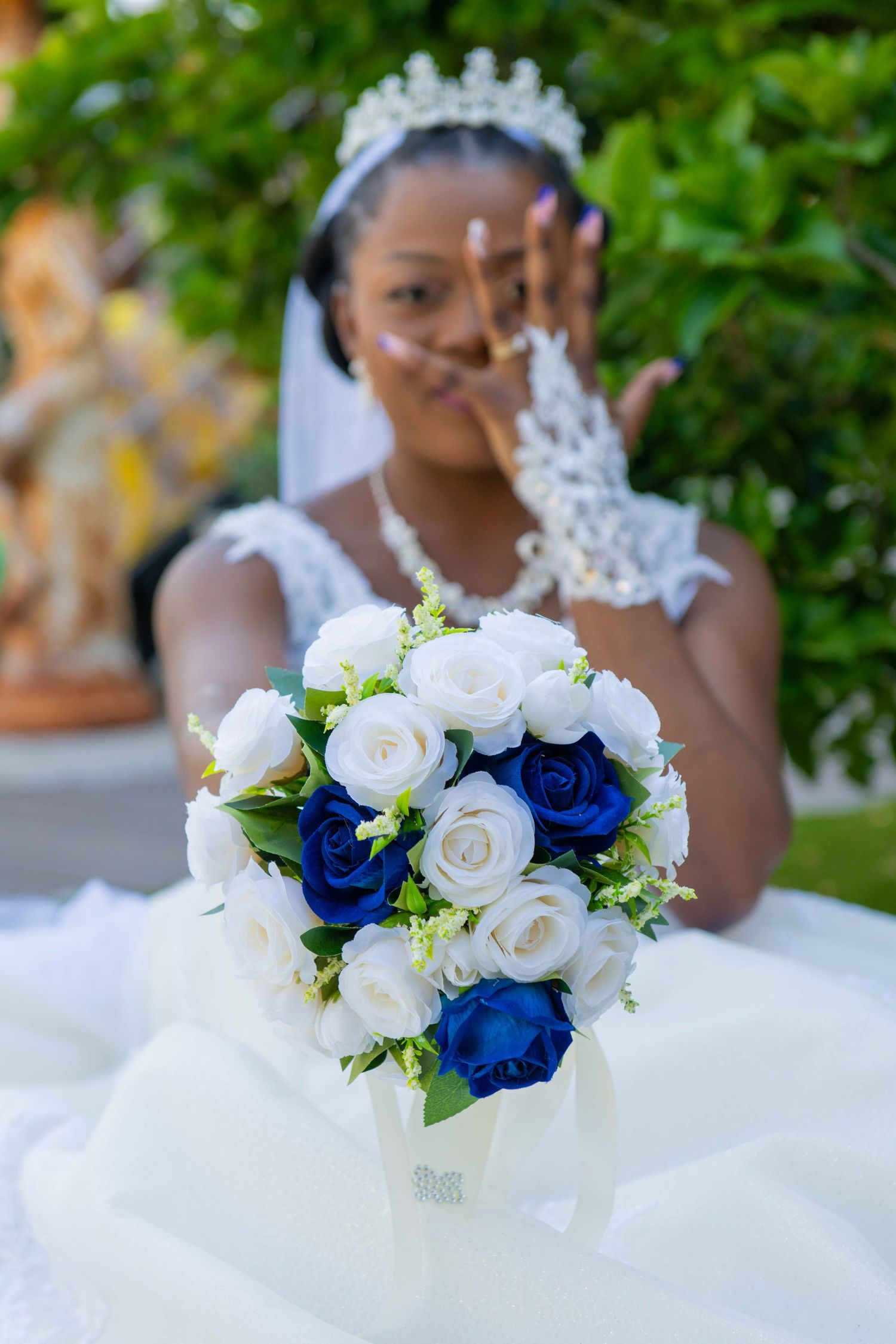 A stunning bridal bouquet featuring white roses and royal blue flowers against a wedding dress background.