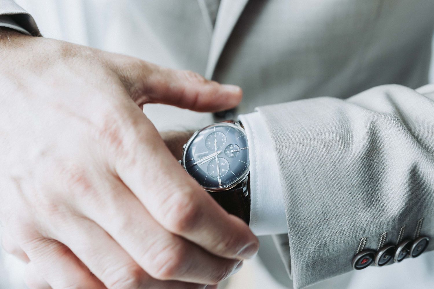 Close up of hands adjusting white dress shirt sleeve cuffs and buttons.