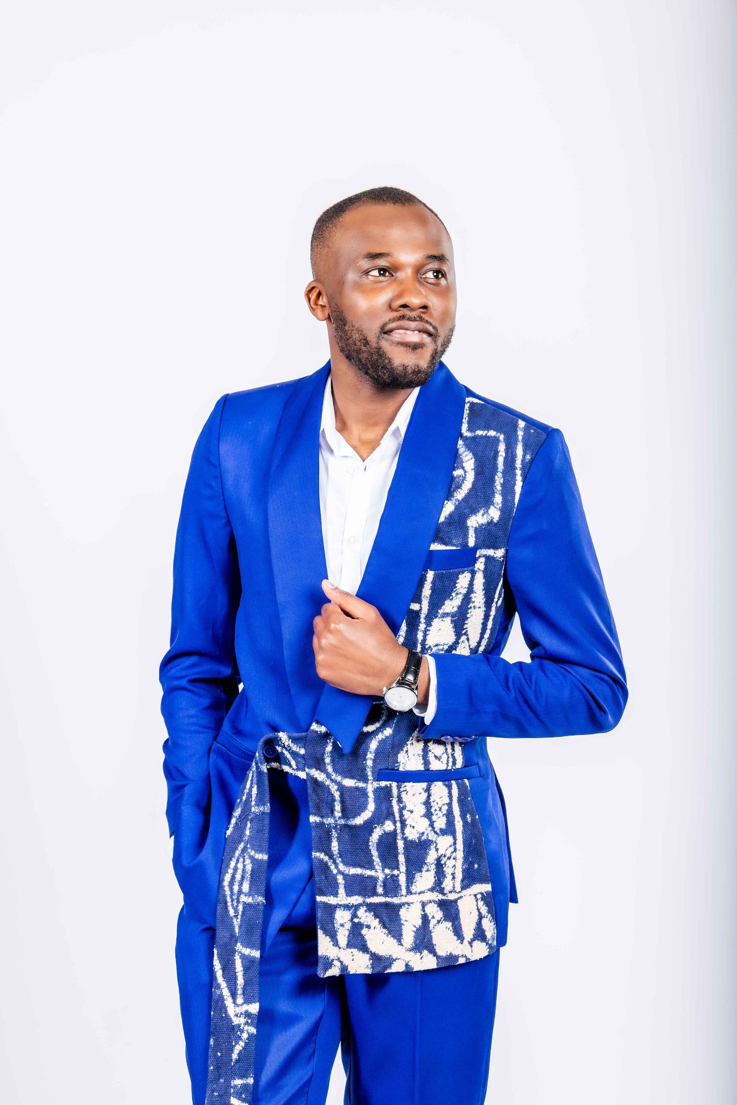 Model poses in vibrant royal blue blazer with abstract white pattern detail against white background.