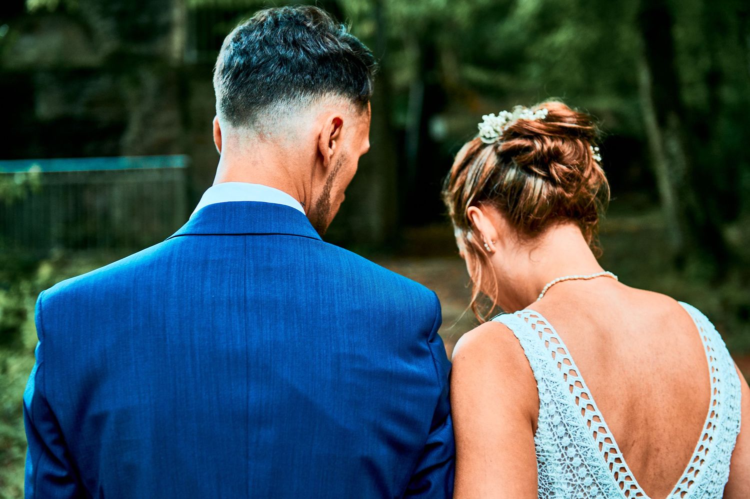 A couple in formal attire at a wedding, with the bride in a sparkly dress and groom in a navy blue suit.