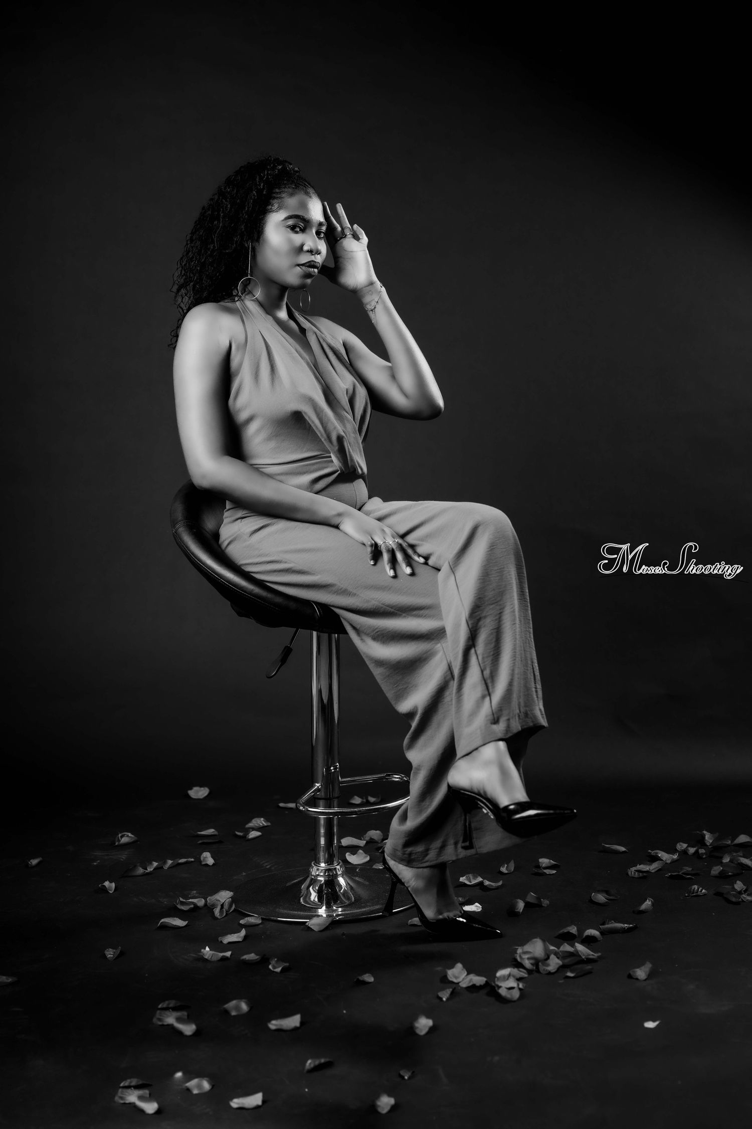 Dramatic black and white photo series shows a seated figure in flowing dress surrounded by scattered rose petals on dark floor.