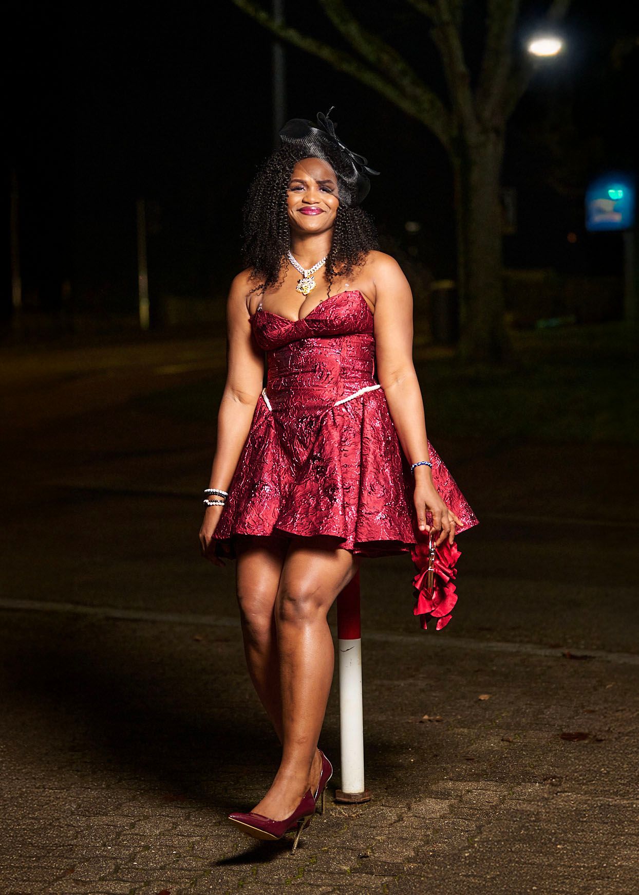 A person in a burgundy velvet dress poses outdoors at night in a series of artistic shots.
