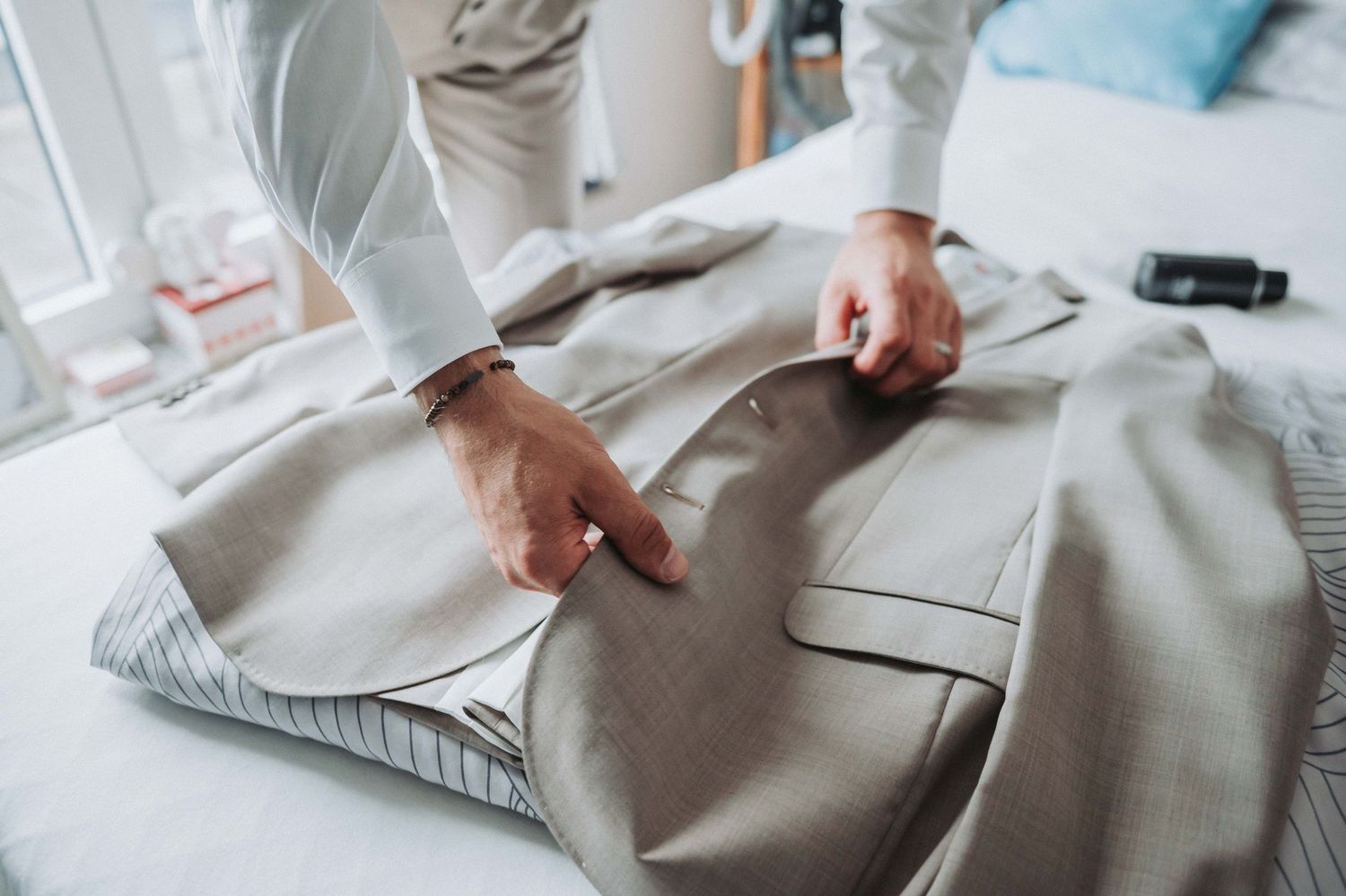 Close-up view of hands adjusting a white dress shirt sleeve with precision and care.