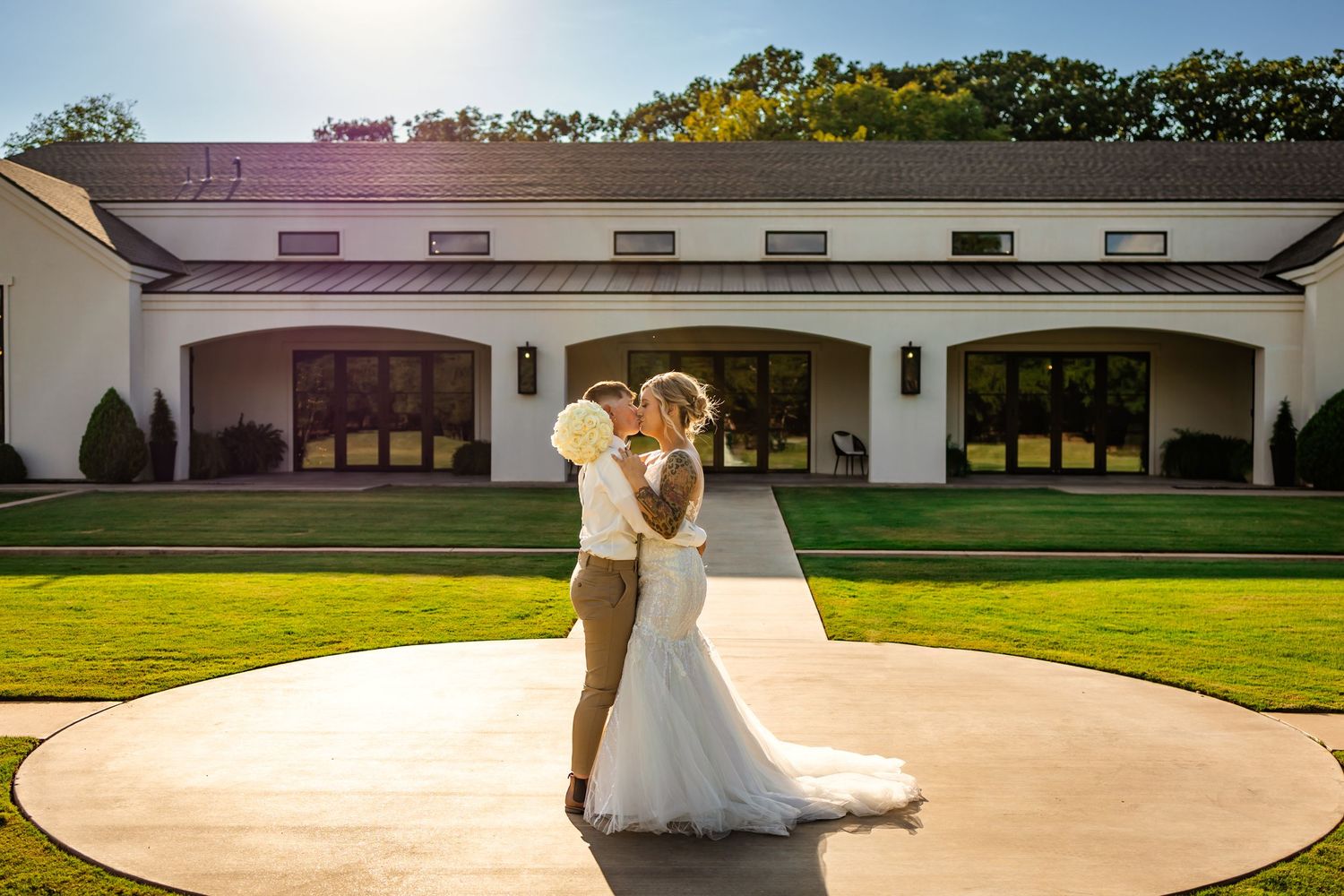 brides share a kiss in front of Oklahoma wedding venue sorelle in Thomas. wedding photography.