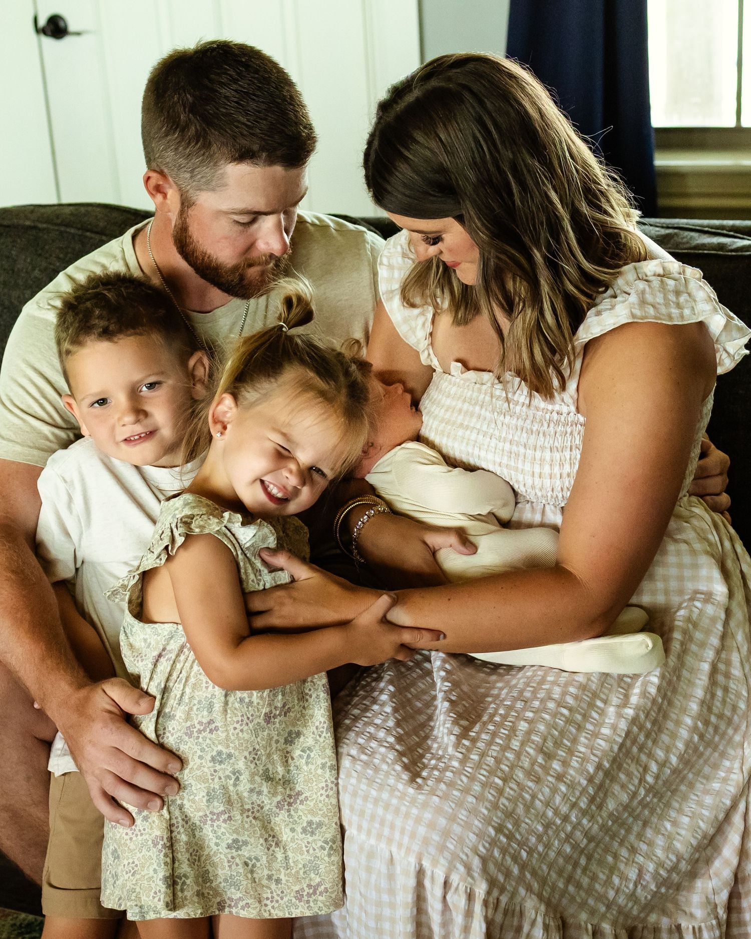 A happy family of 5 sharing a warm embrace, with parents cuddling three young children in a home setting. family photographer in Oklahoma
