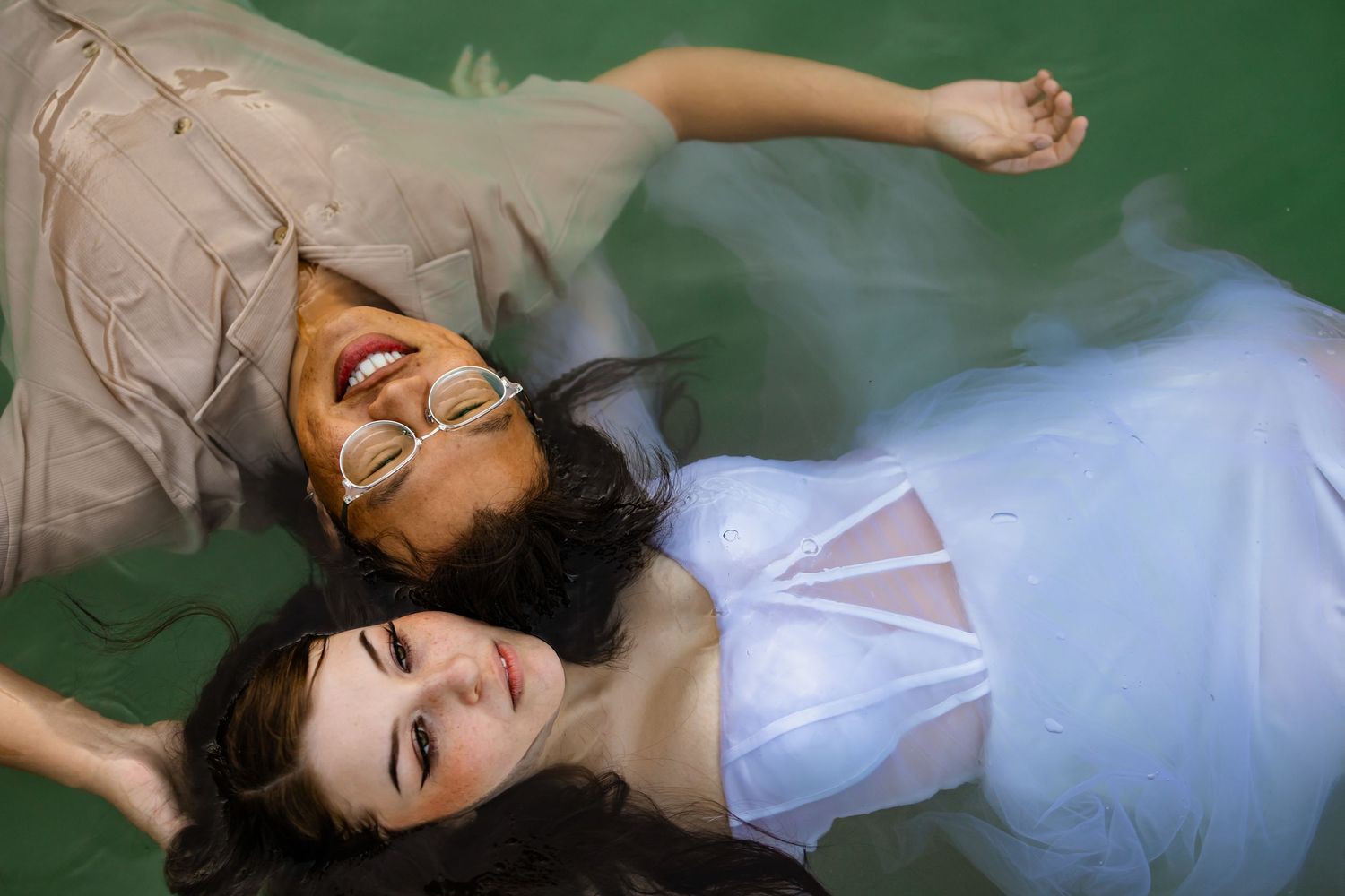 Oklahoma couple in elegant dress float gracefully in green water in an artistic fashion photo.