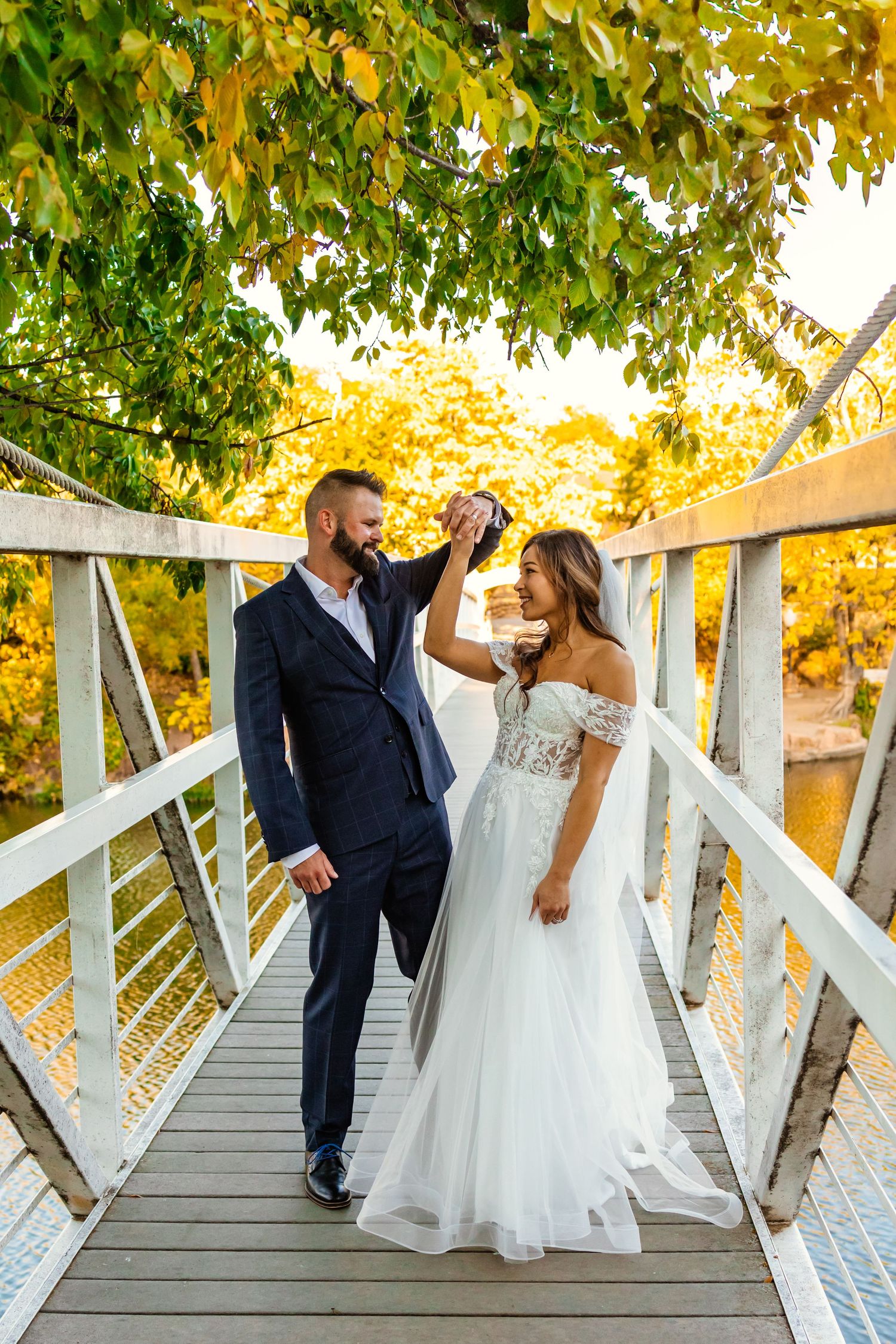 Bride and groom dancing on a wooden bridge surrounded by autumn foliage on their wedding elopement day in medicine park, Oklahoma.