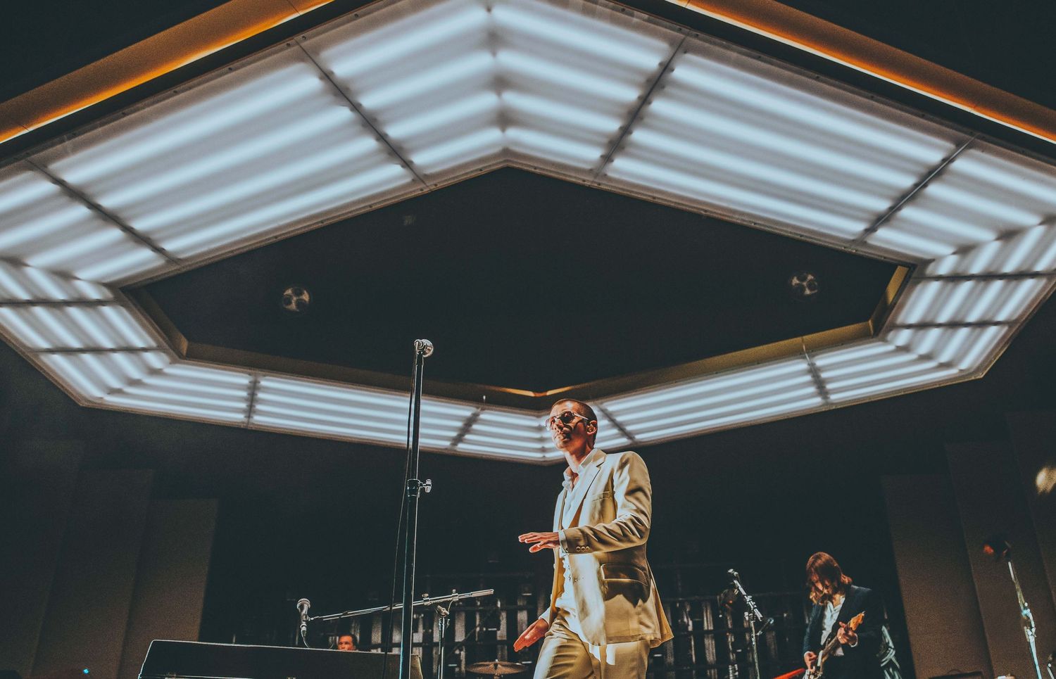 Concert venue with modern ceiling lighting design and Arctic Monkeys on stage, directed by Ant Barrett (RESOLVE FILM)