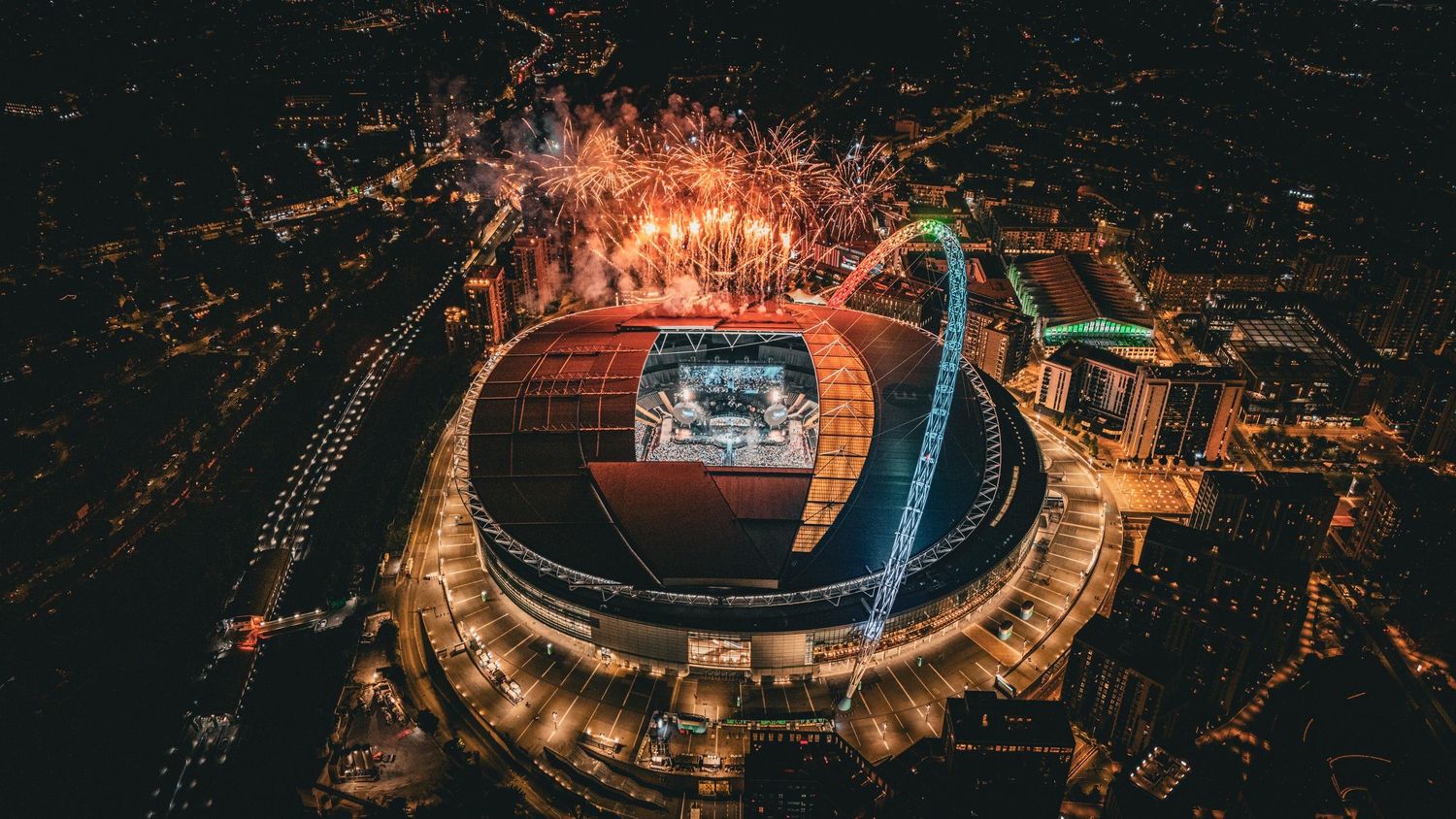 Panoramic aerial view of a city stadium lit up at night during a Coldplay concert, directed by Ant Barrett (RESOLVE FILM)