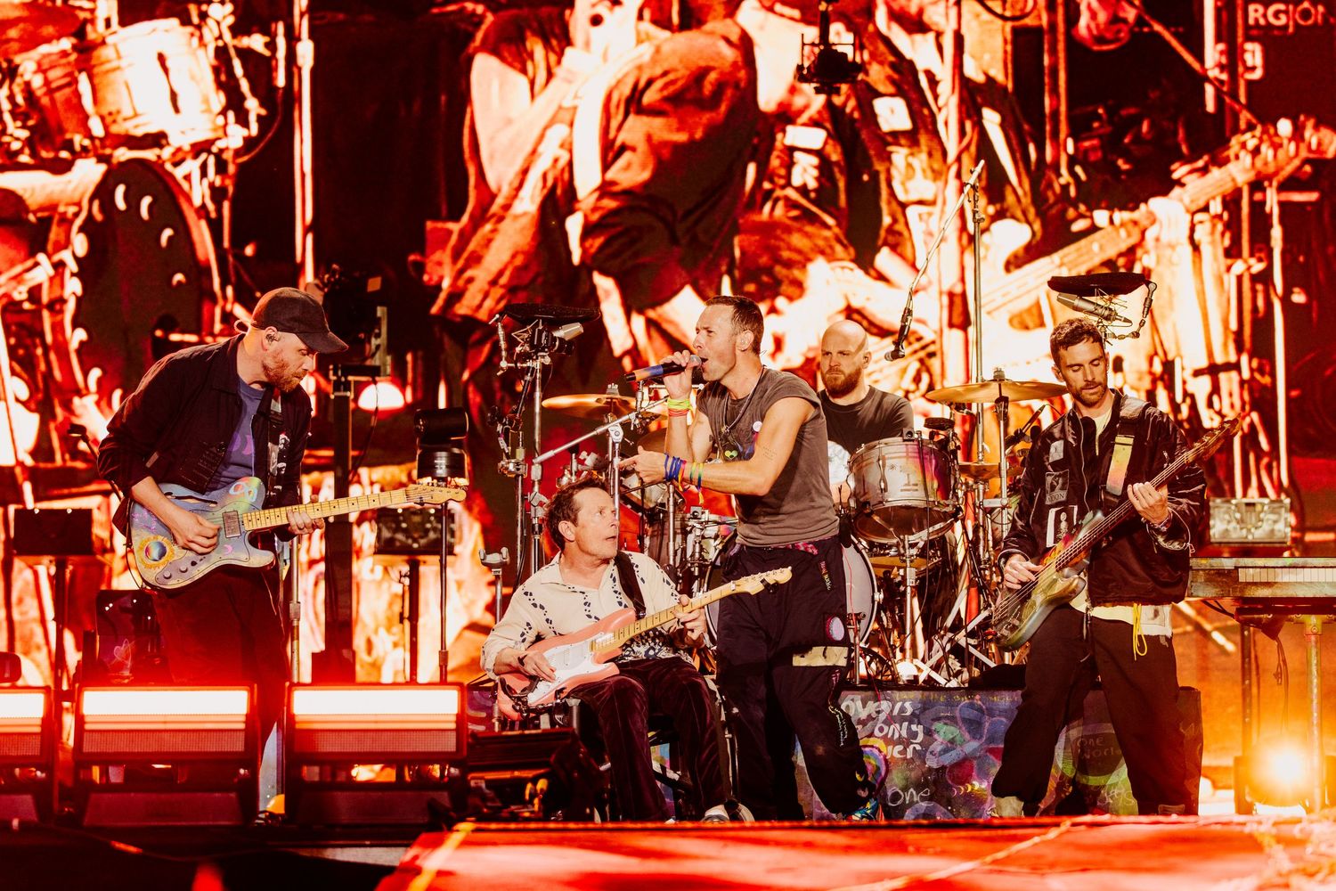 Coldplay performing on stage with dramatic red lighting and energetic atmosphere, directed by Ant Barrett (RESOLVE FILM)