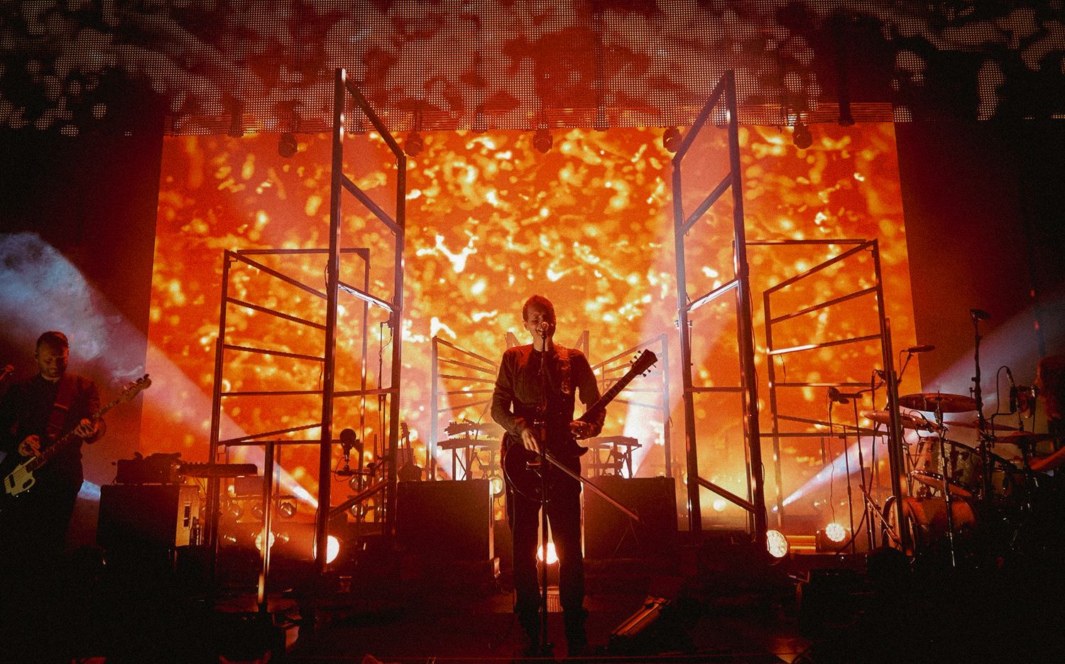 Silhouetted performer Jonsi of Sigur Ros on stage with intense orange lighting and flames in the background, directed by Ant Barrett