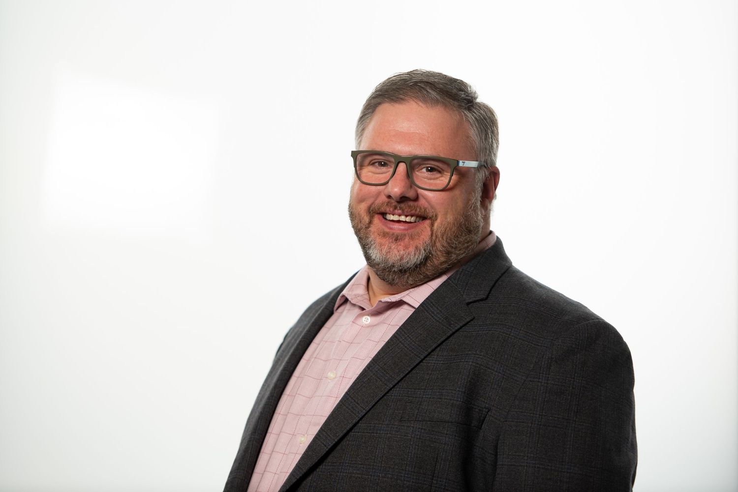 Professional headshot of a person wearing glasses, a pink dress shirt and dark blazer smiling in Boston, MA with Leah Ramuglia Photography