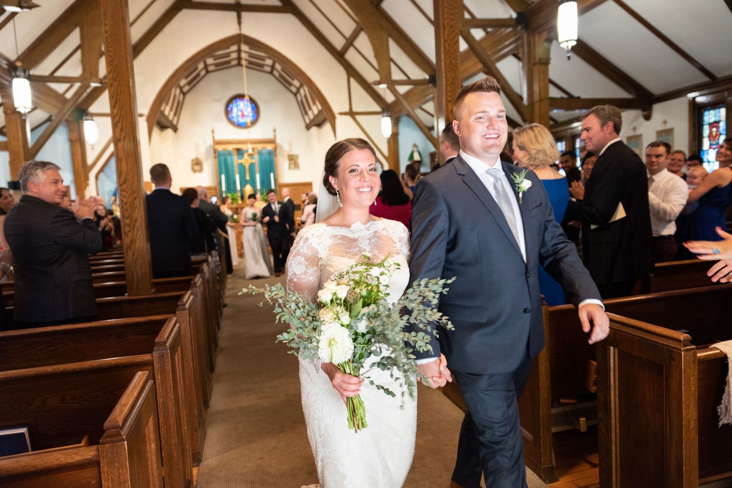 Newlyweds walk down the aisle of a St. Patrick's Church in Newport, NH after their beautiful wedding ceremony with Leah Ramuglia Photography