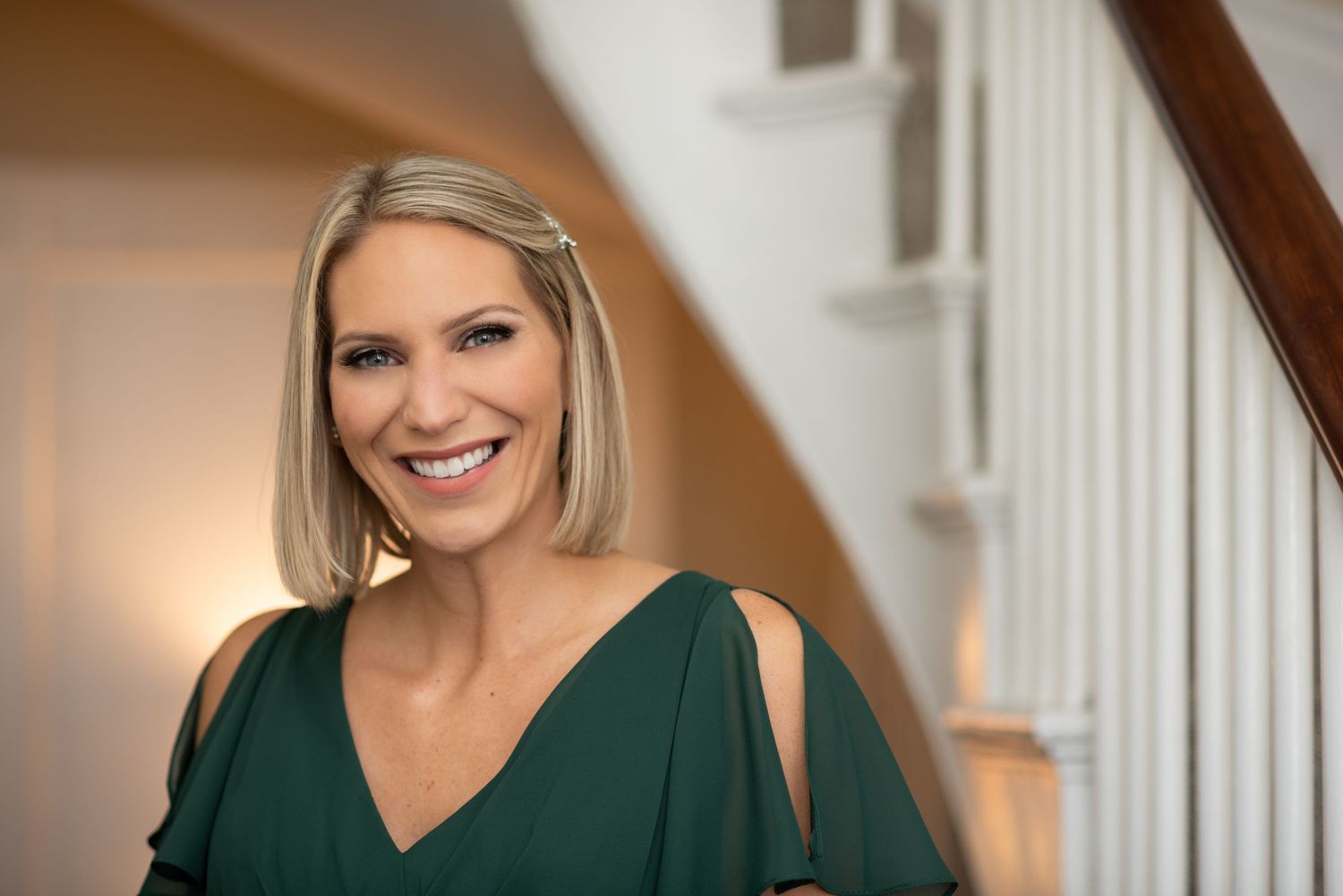 Professional portraits of a woman in a dark green dress standing by a white staircase with Leah Ramuglia photography.