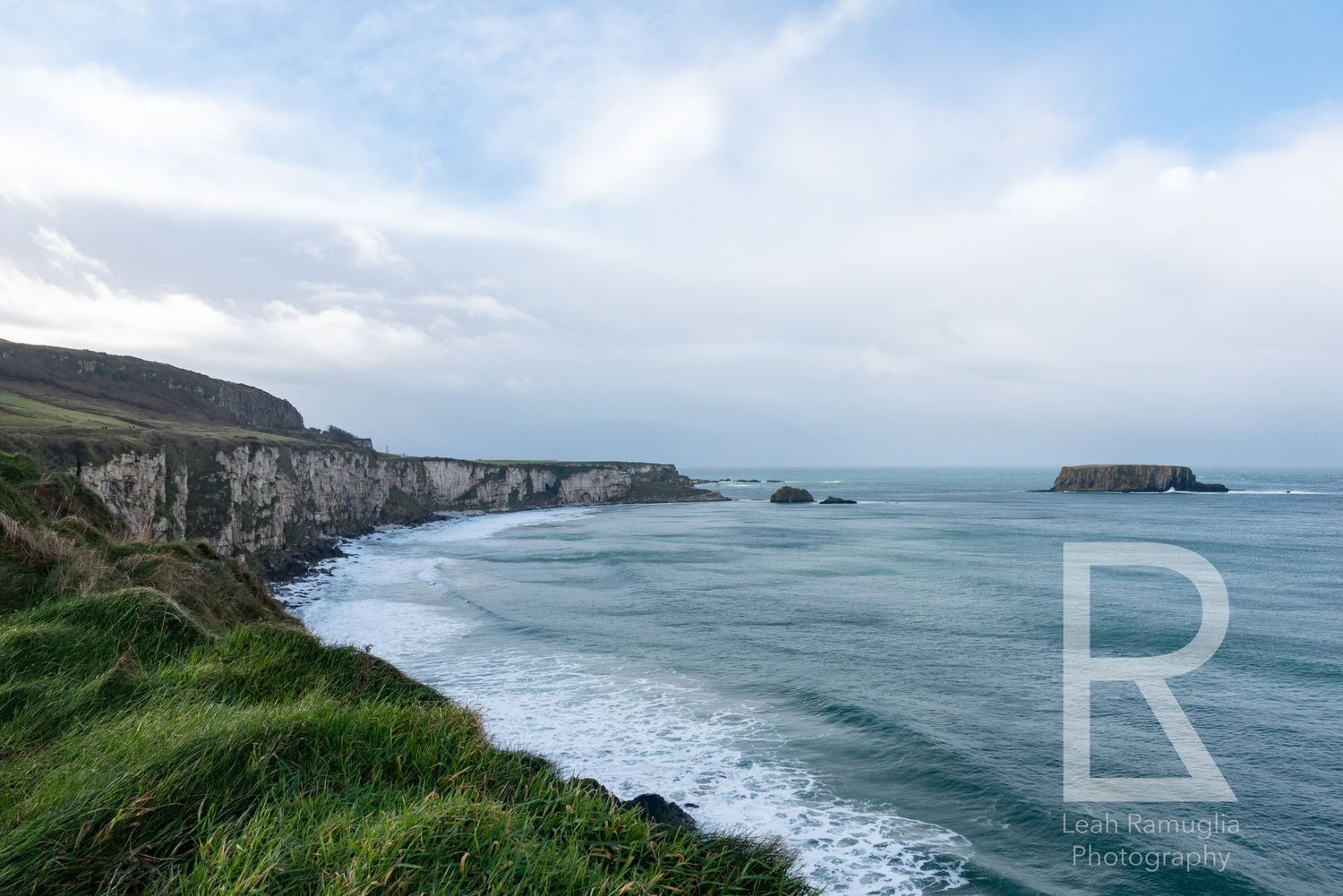Dramatic coastal landscape Northern Ireland's Causeway Coast with rugged cliffs & crashing waves against rocky shores. Leah Ramuglia Photo