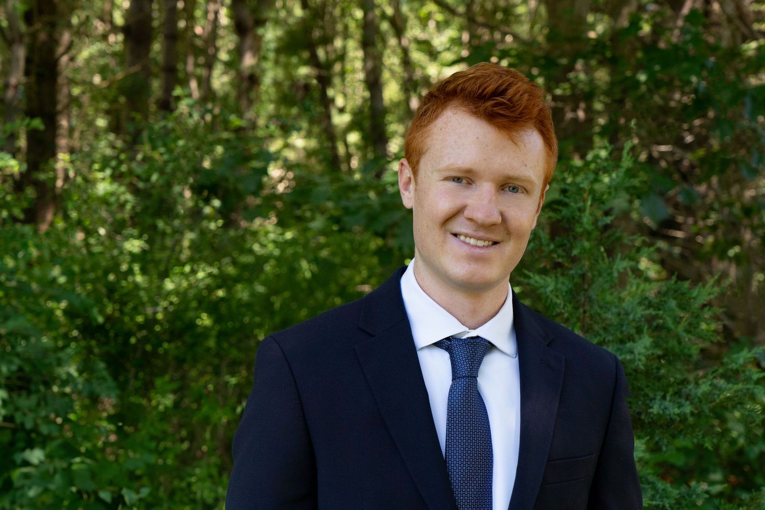 Men’s professional headshots in Hanover, MA with Leah Ramuglia Photography. A Red head with a blue suit and forest green background.
