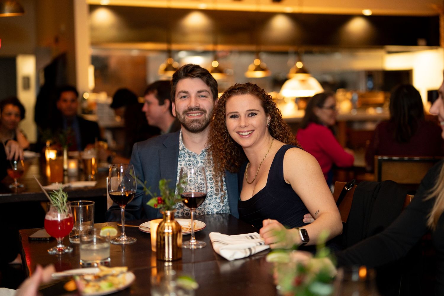 People enjoying drinks & conversation at a cozy restaurant bar at the Arsenal in Watertown during an office holiday party with Leah Ramuglia