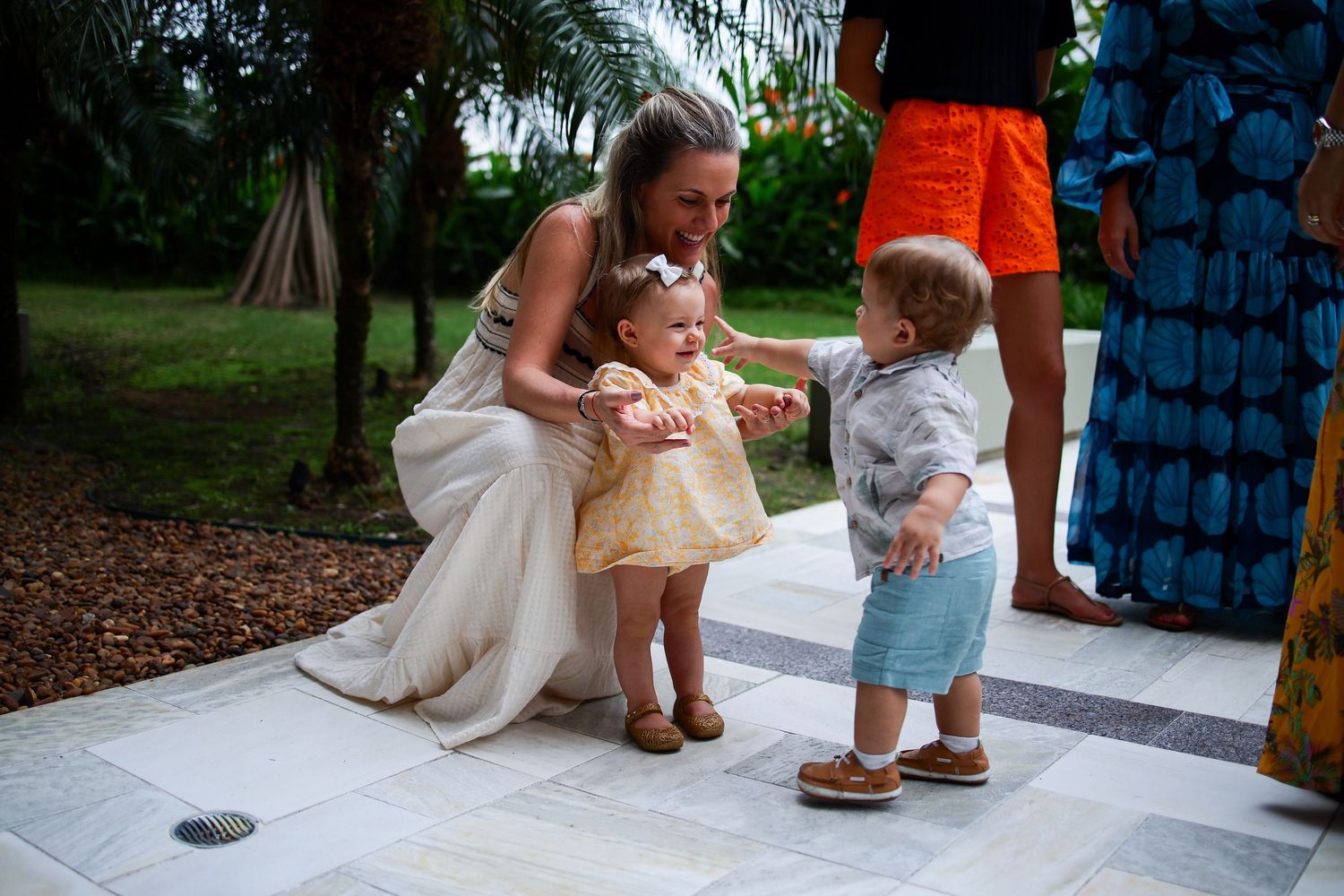 Wedding moment captured at outdoor reception with small children and palm trees in background.