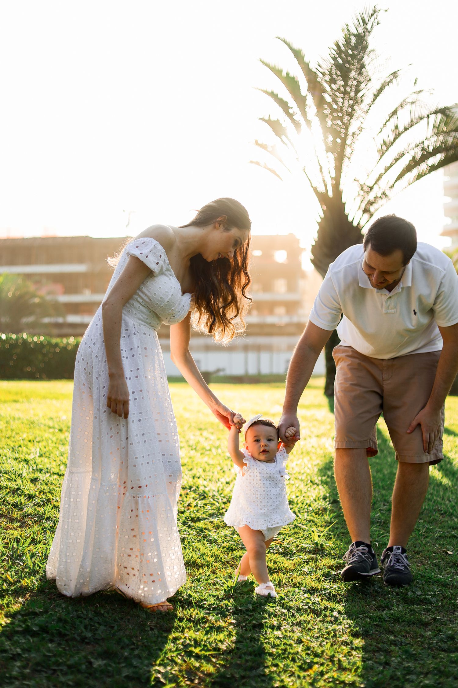 Family in white and brown outfits explore a grassy meadow together at sunset, creating candid moments in nature.