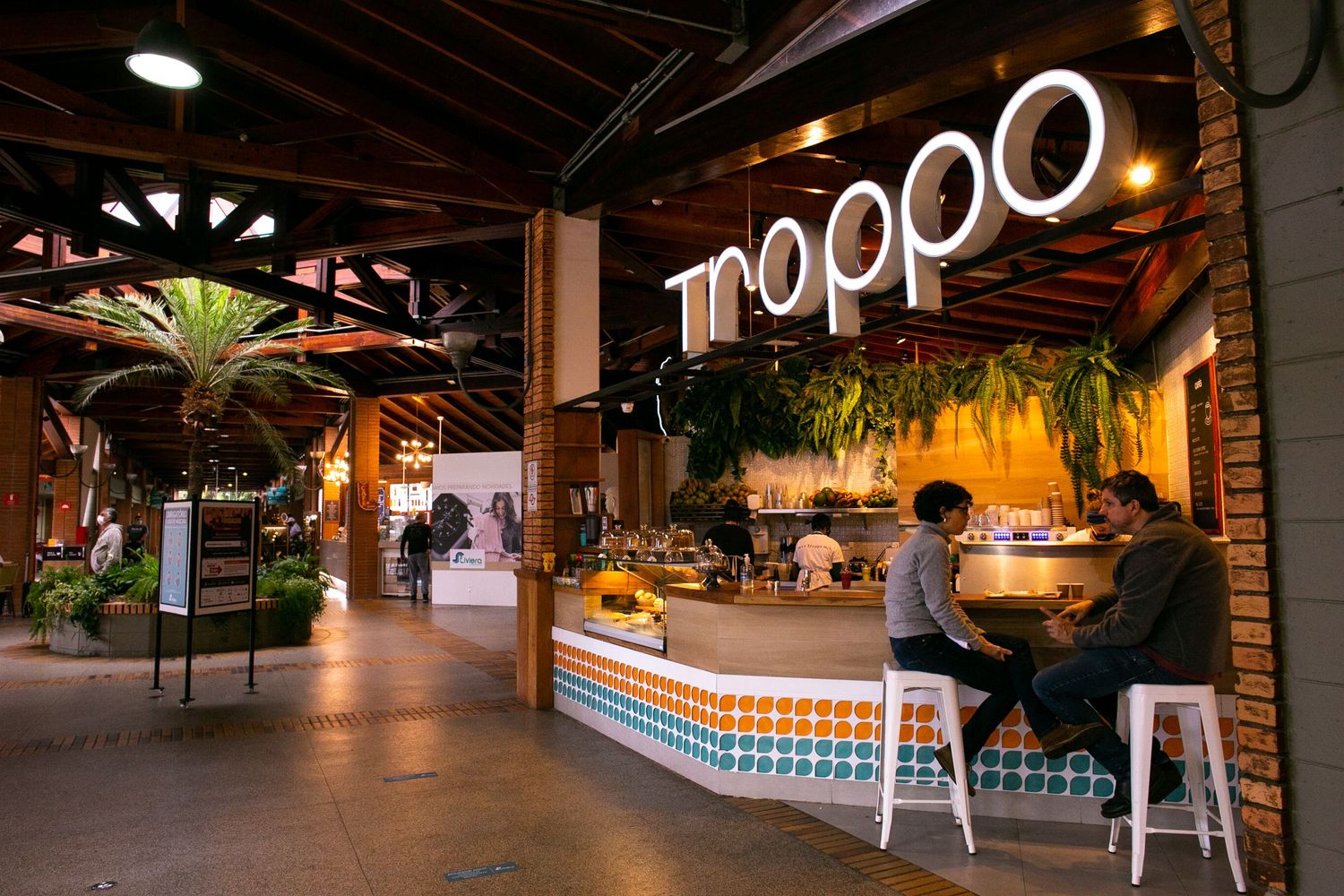 Modern restaurant Tropo with illuminated signage and a stylish bar counter in a dimly lit industrial-style space.