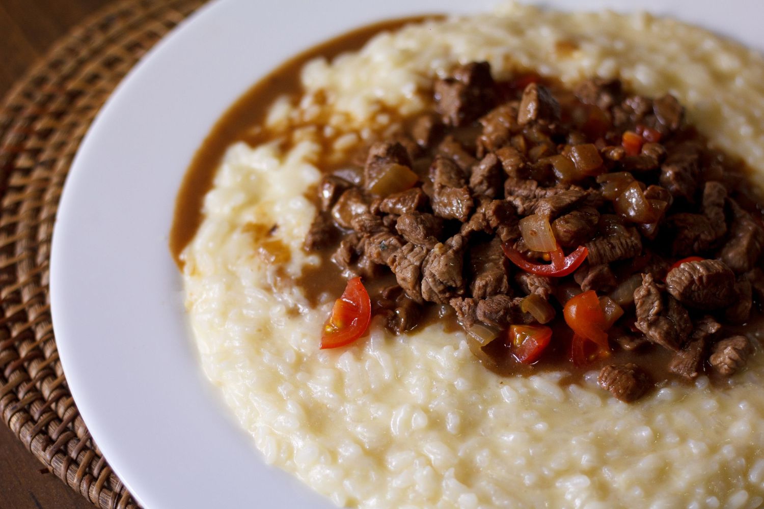 Creamy mashed potatoes topped with tender beef stew and colorful carrots served on a white plate.