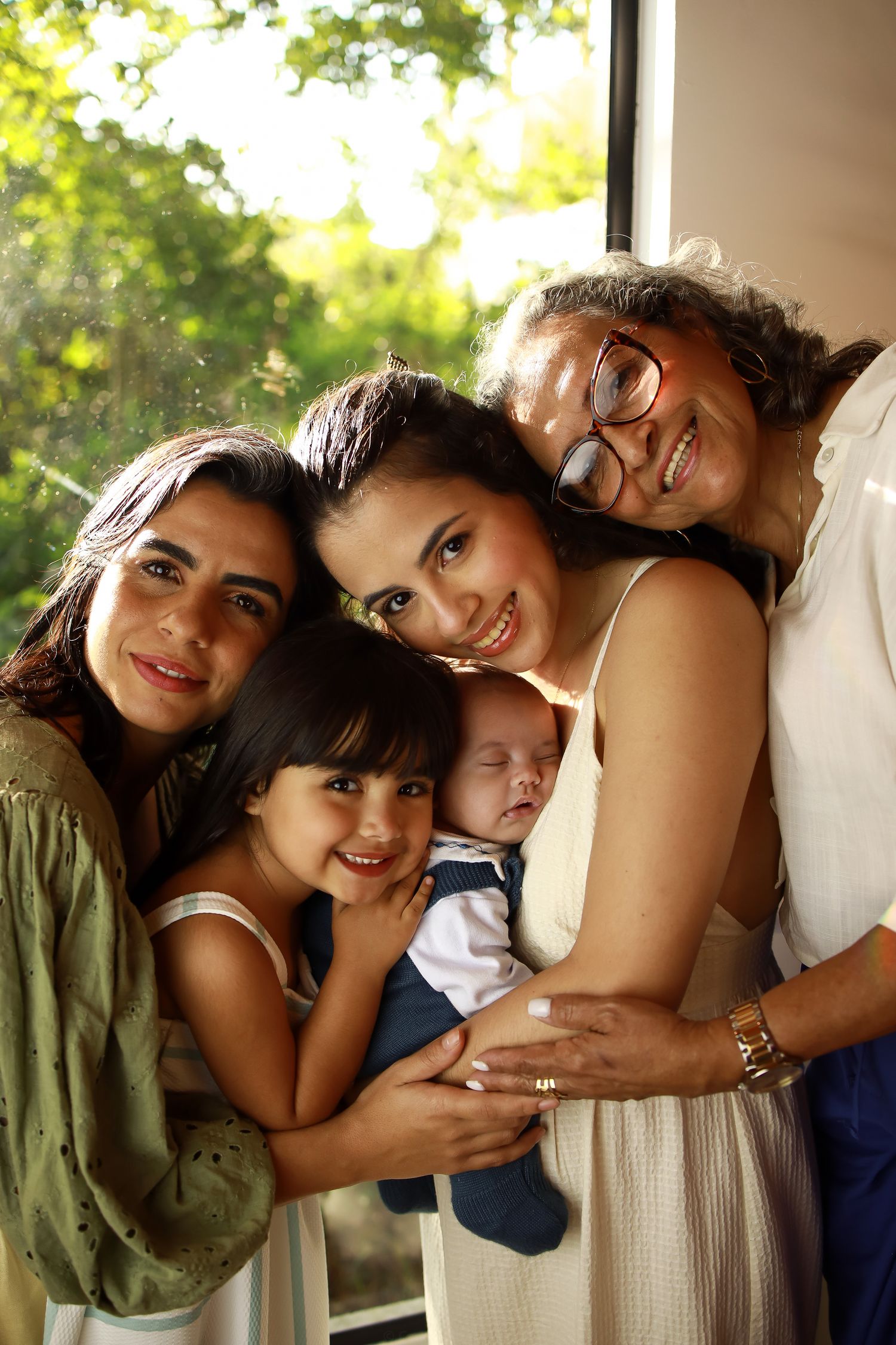 A family embraces in warm light by a window, sharing tender smiles and laughter together.