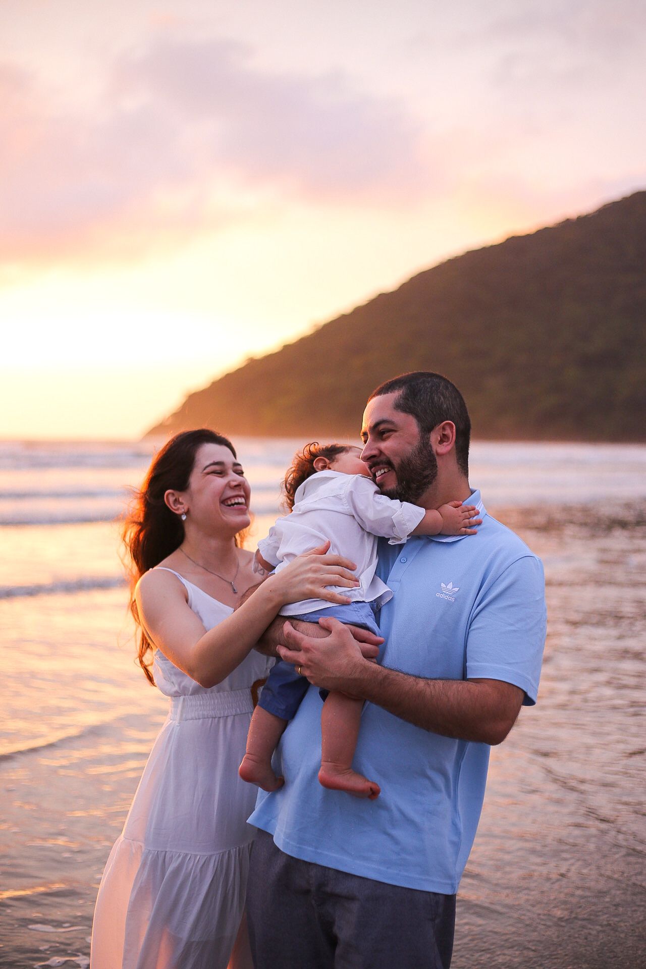 Happy family sharing a joyful moment together on the beach at sunset with mountains in the background.