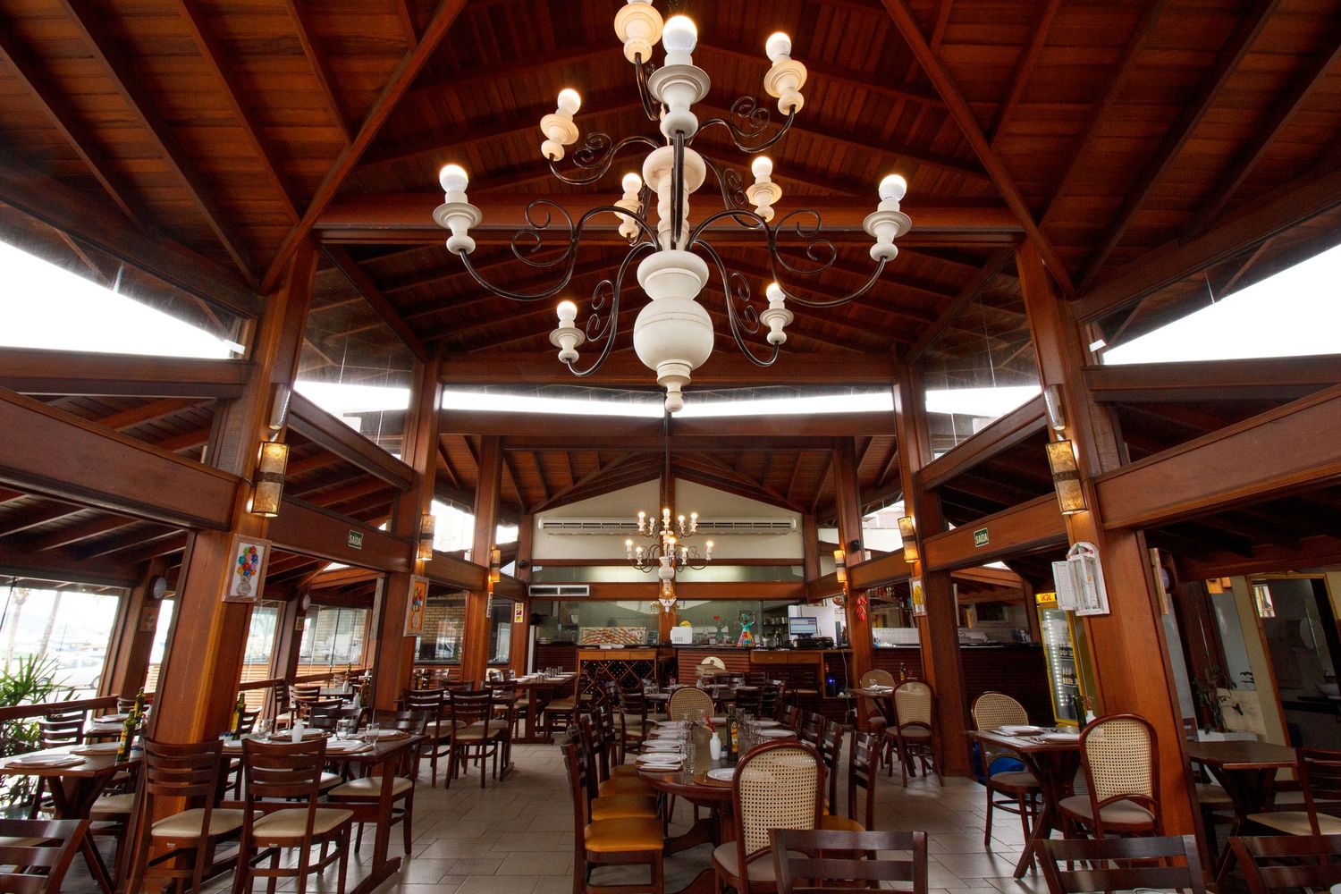 Upscale dining room with rustic wooden architecture features ornate chandeliers and comfortable seating arrangements.
