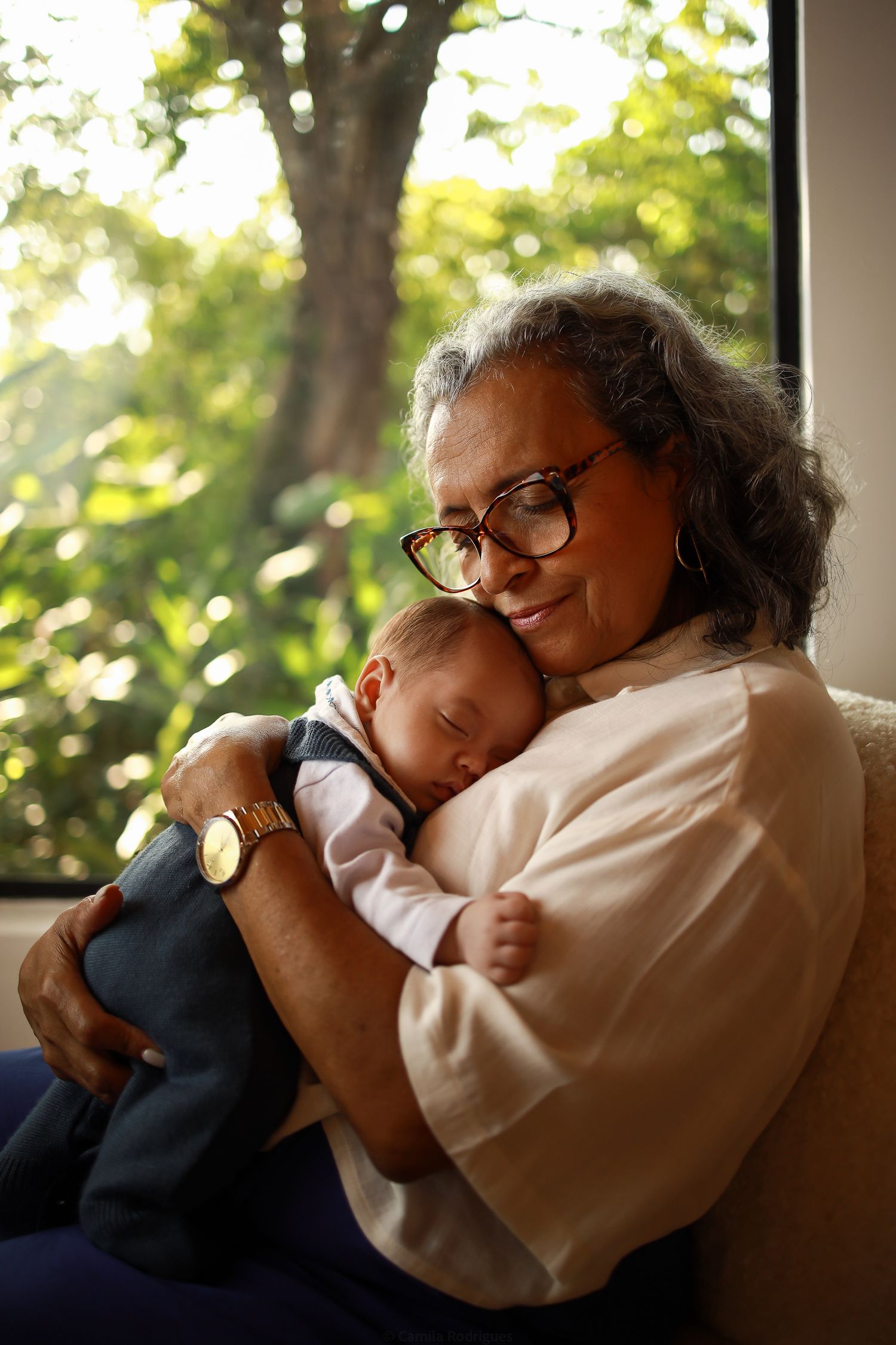A peaceful moment captured as a baby sleeps contentedly in a warm embrace near a sunlit window.