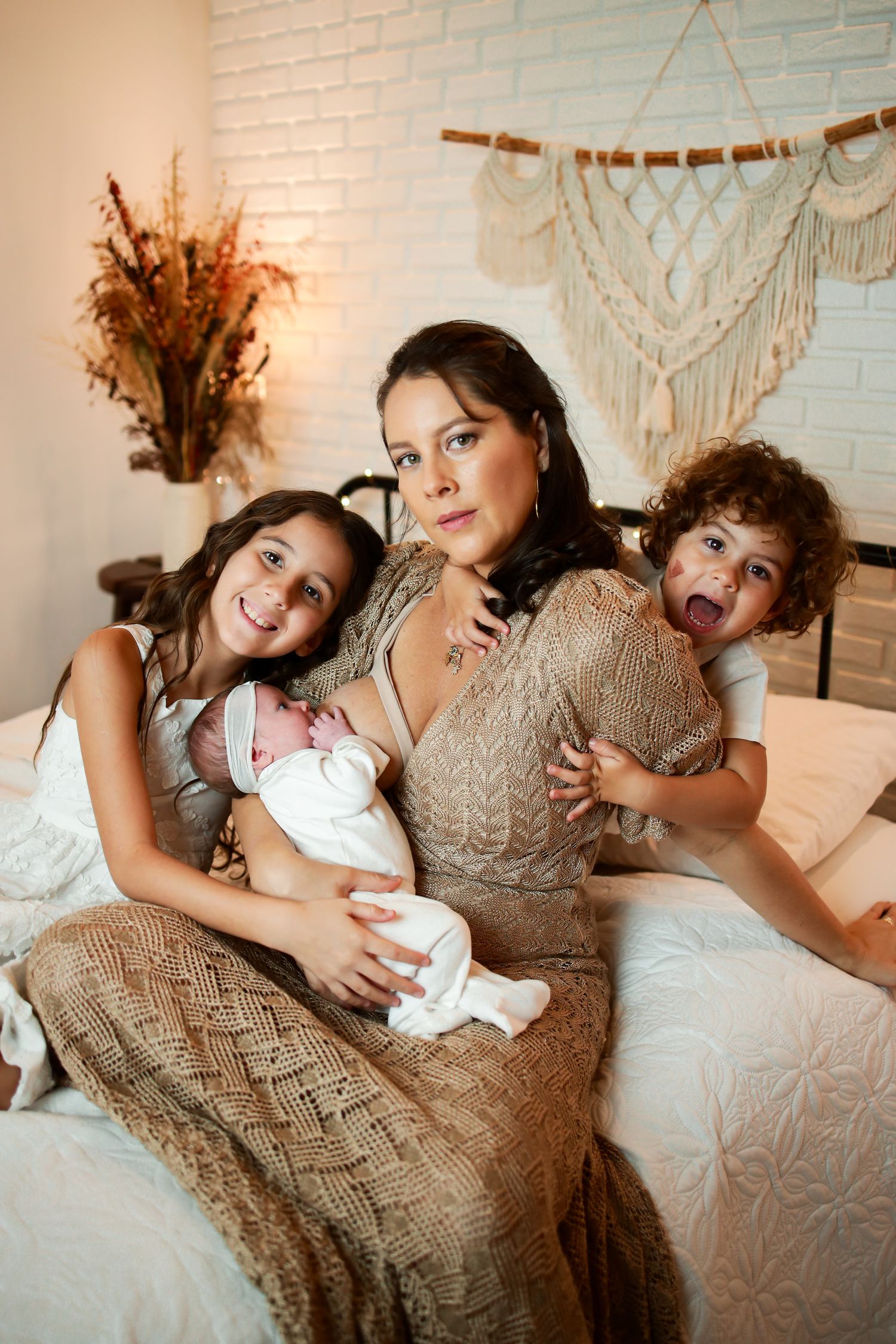 A family sitting together on a couch with macrame wall decor and dried flowers in the background.