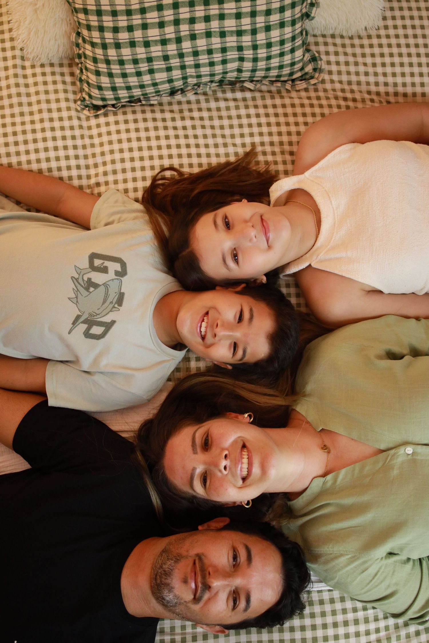 Four smiling people laying down and looking upward in a casual photo on a checkered surface.