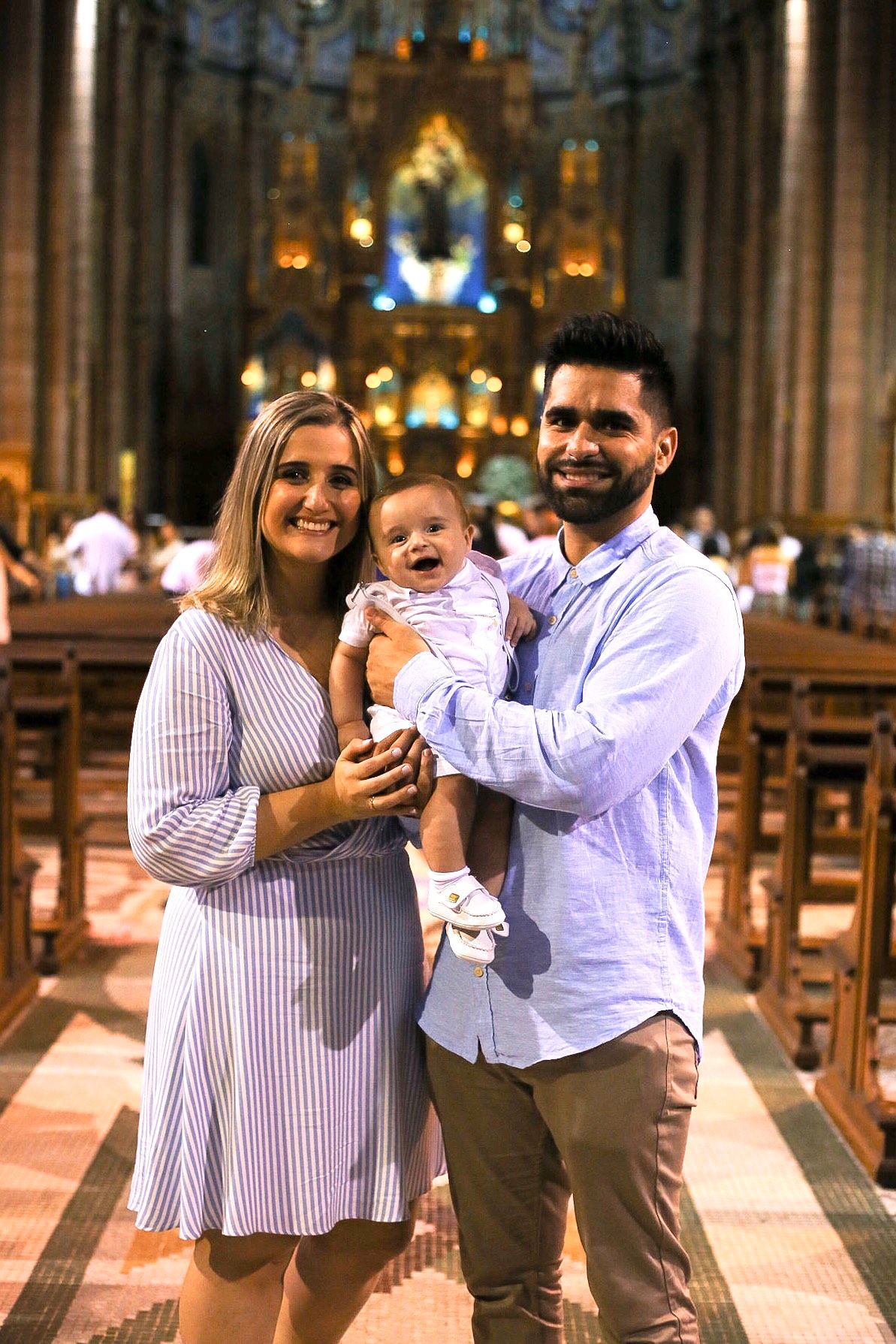 Family standing in a church aisle with ornate altar and stained glass windows in the background.