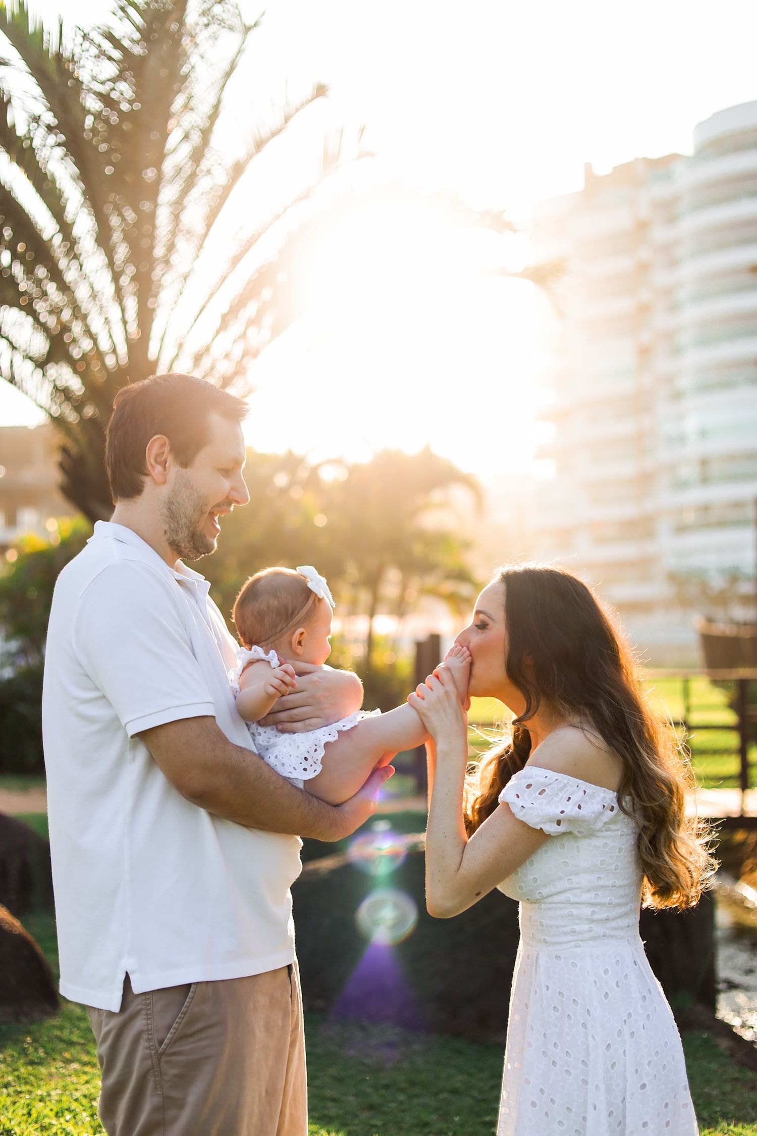 Family shares joyful moment outdoors during golden sunset in front of modern buildings.