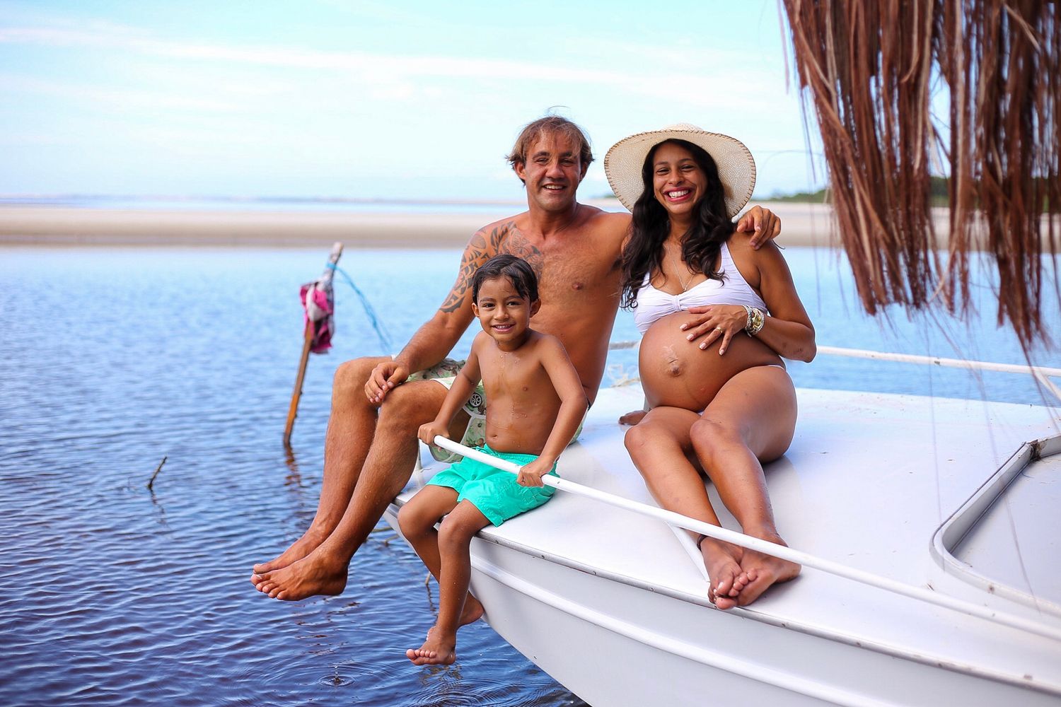 Happy family relaxing on boat deck near tropical beach with calm waters and blue sky in summer.