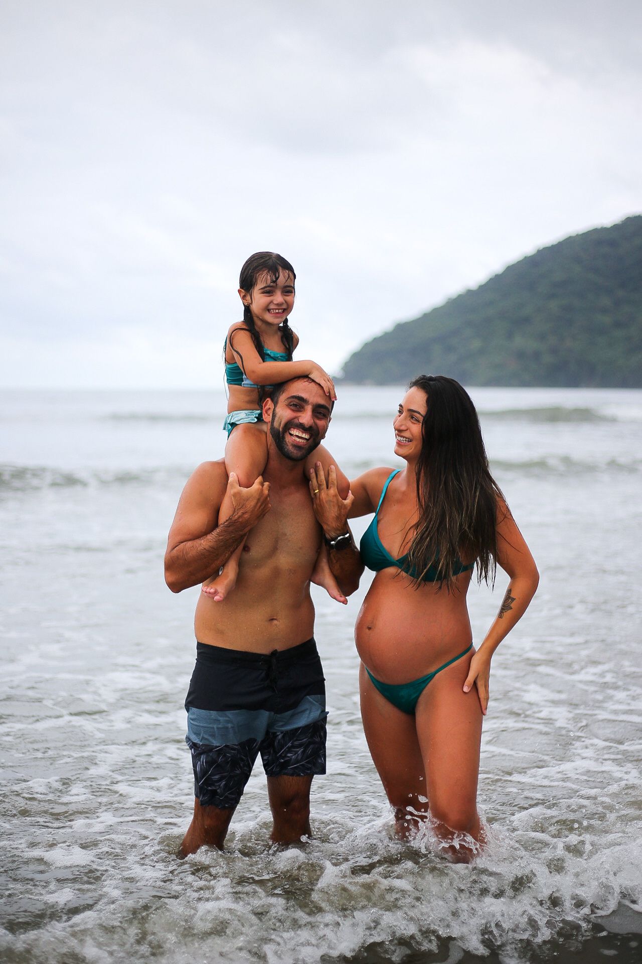 A family enjoys time together in the ocean waves on a cloudy day at the beach.