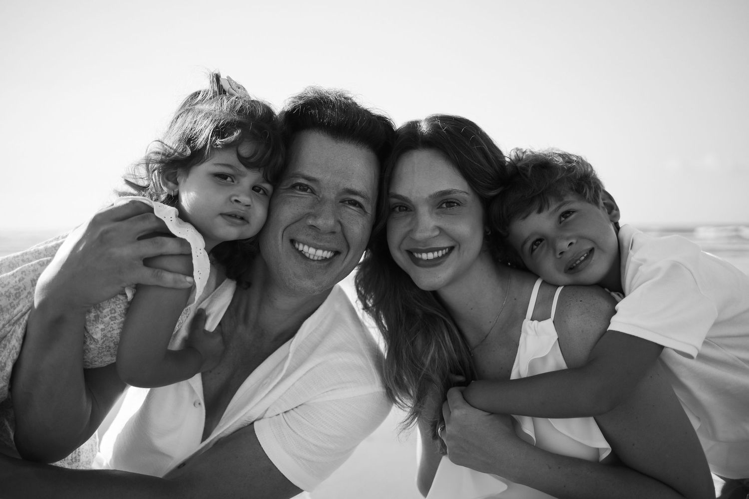 Black and white portrait of family members embracing outdoors.