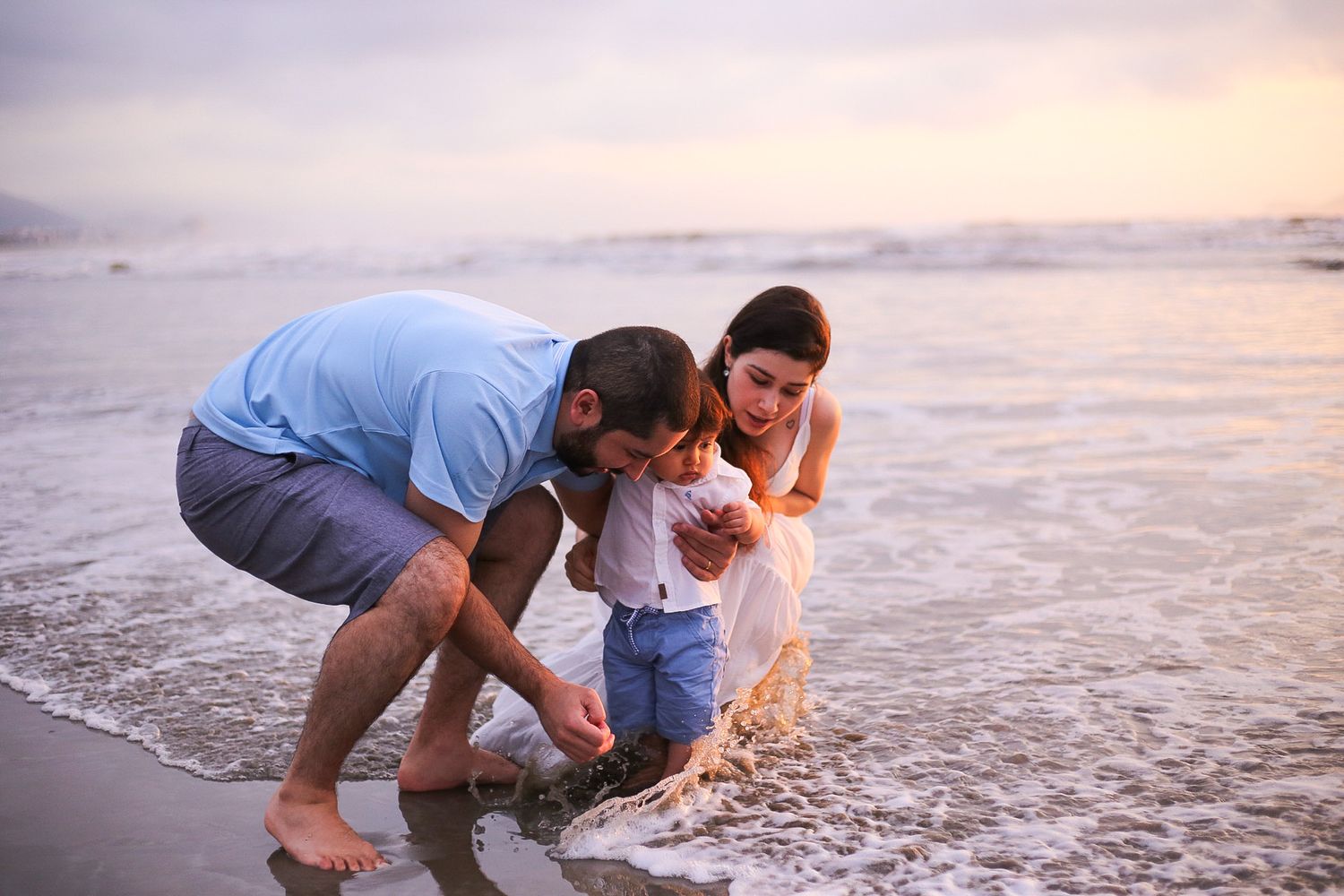 Family explores the beach at sunset as waves gently wash onto shore and create a peaceful seaside moment.