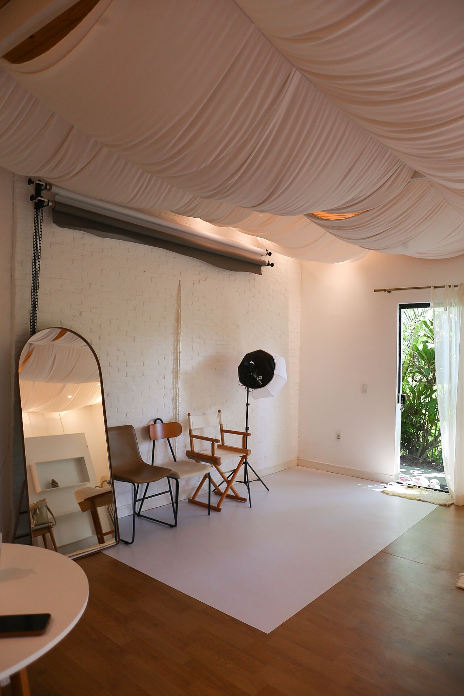 Professional photography studio interior with white cyclorama wall, wooden floors, and natural lighting from windows.