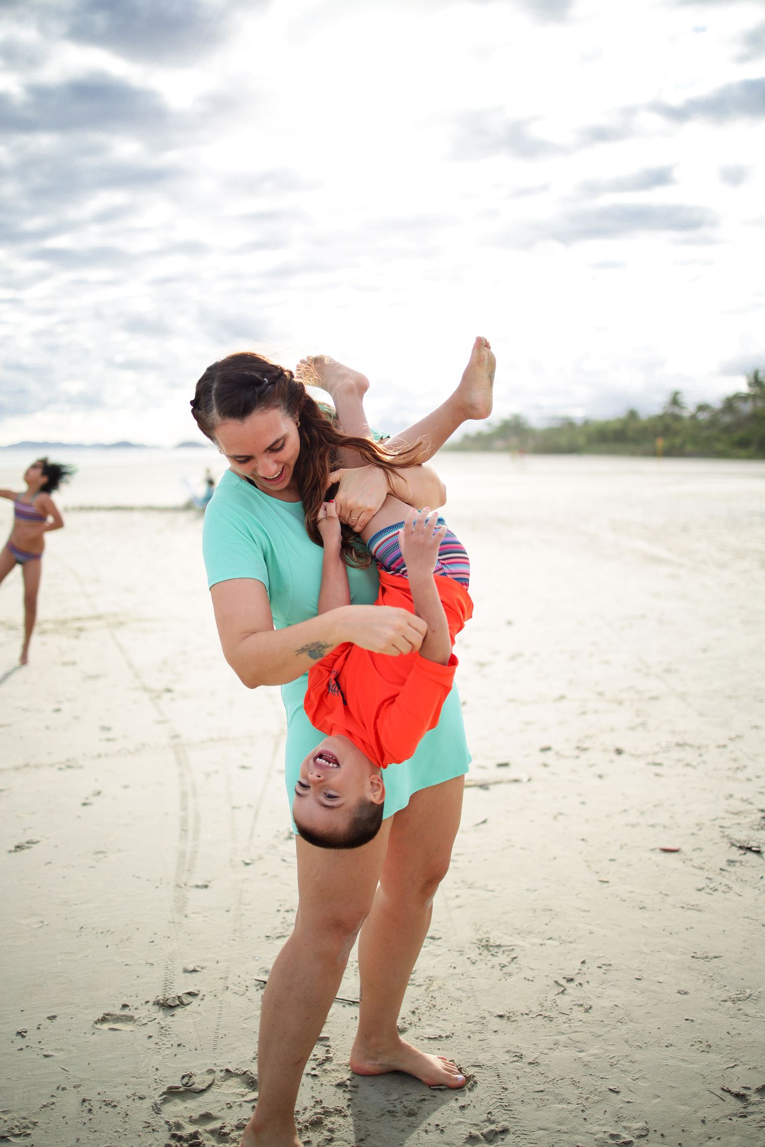 Family plays and dances together in a series of joyful candid moments on a peaceful sandy beach.