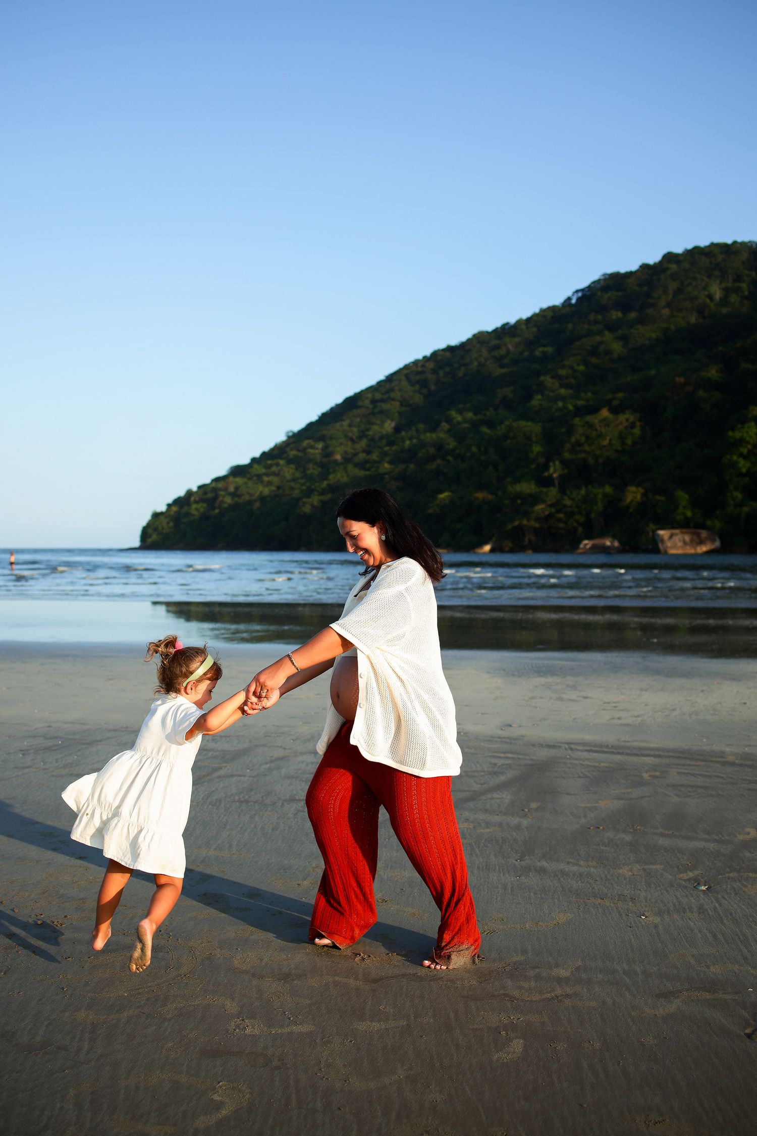 A playful dance on the beach with a mountain backdrop as the evening sun casts long shadows on the sand.