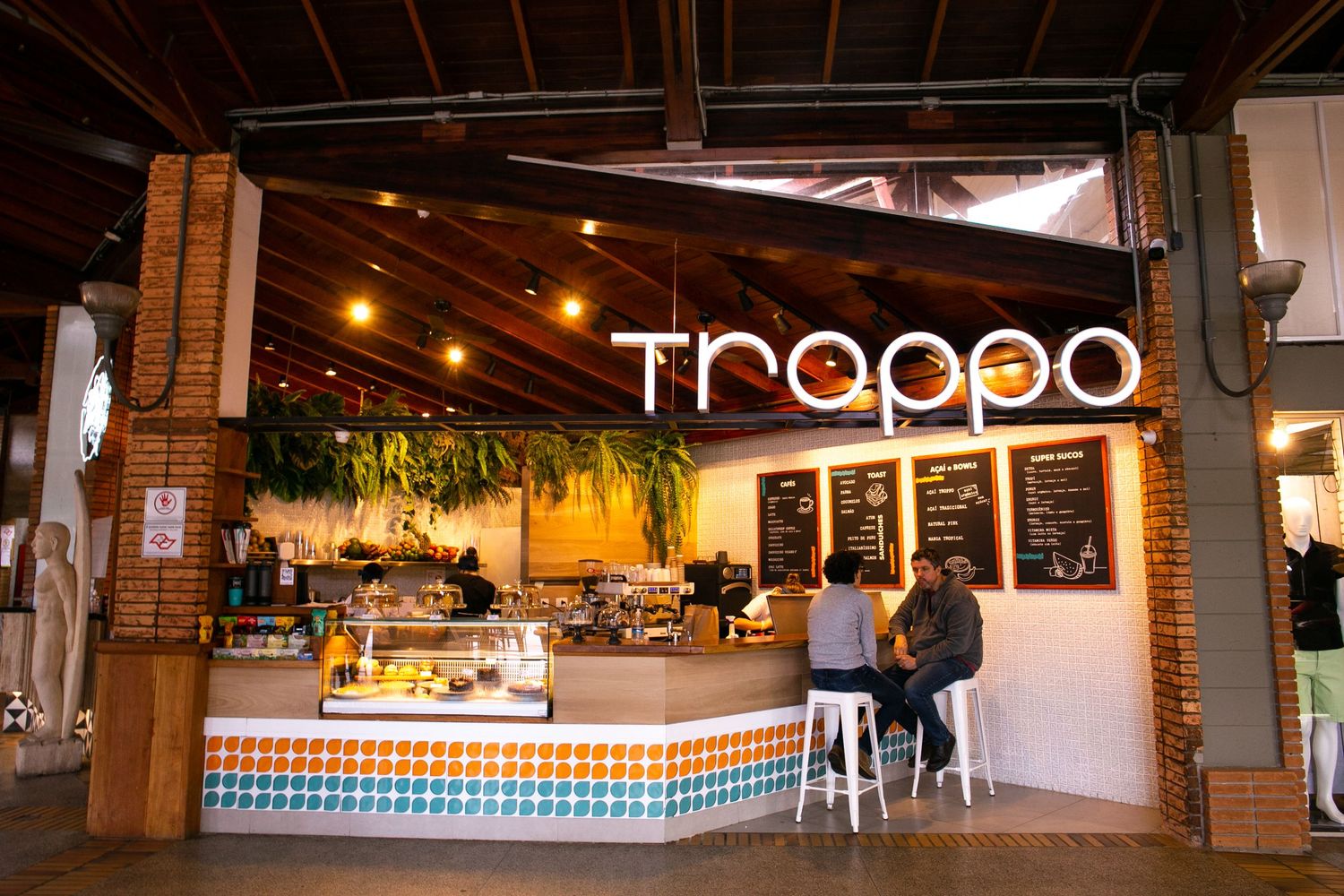 Modern cafe Trappo with illuminated signage features a welcoming interior with warm lighting and colorful tiled counter at night.