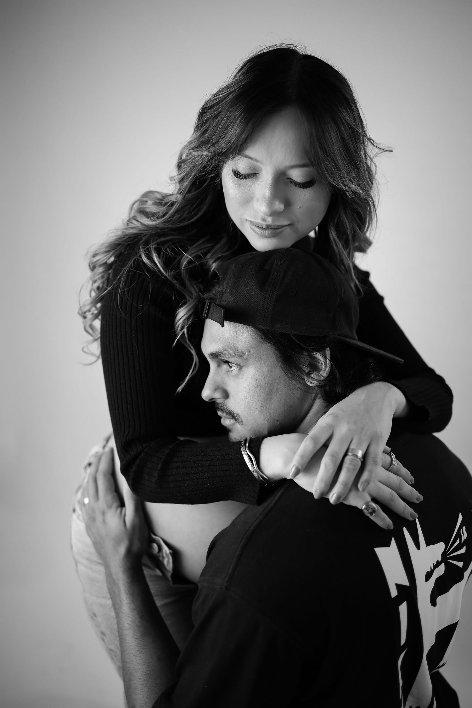 Black and white portrait of an intimate embrace between a couple, with one person wearing a dark sweater and beanie.