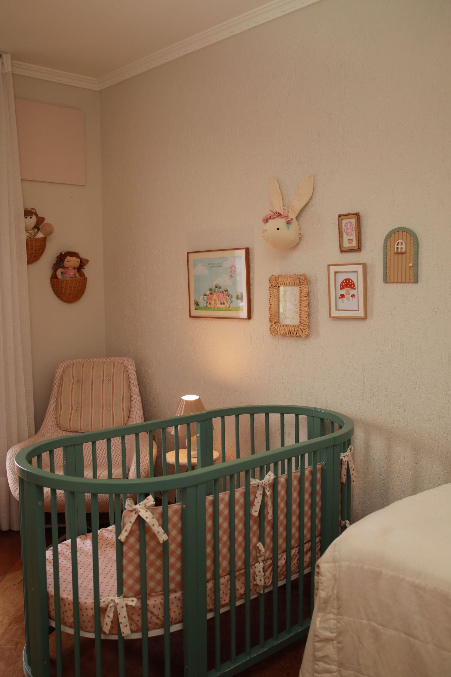 Nursery room with teal oval crib and whimsical wall decor including bunny art and framed pictures.
