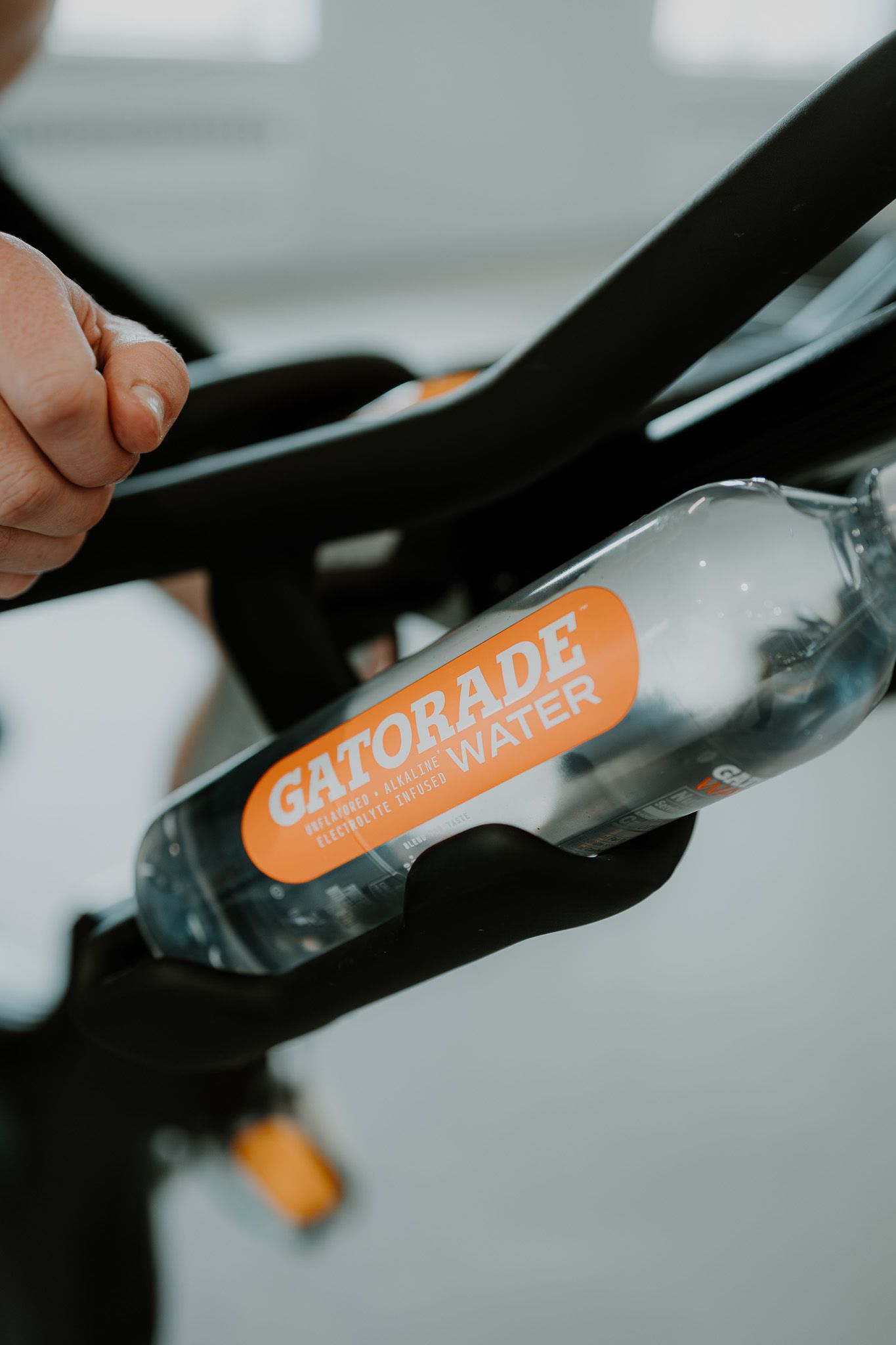 Close-up shot of a clear Gatorade water bottle with orange logo against a blurred background.
