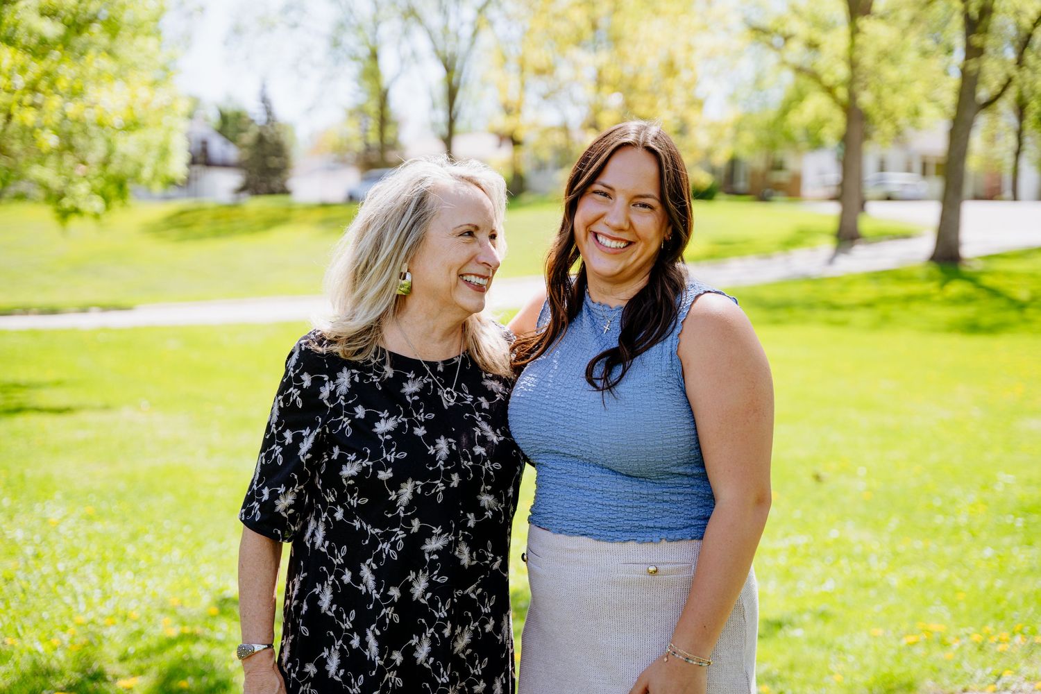 Two people share joyful moments together while standing in a sunny green park on a beautiful spring day.