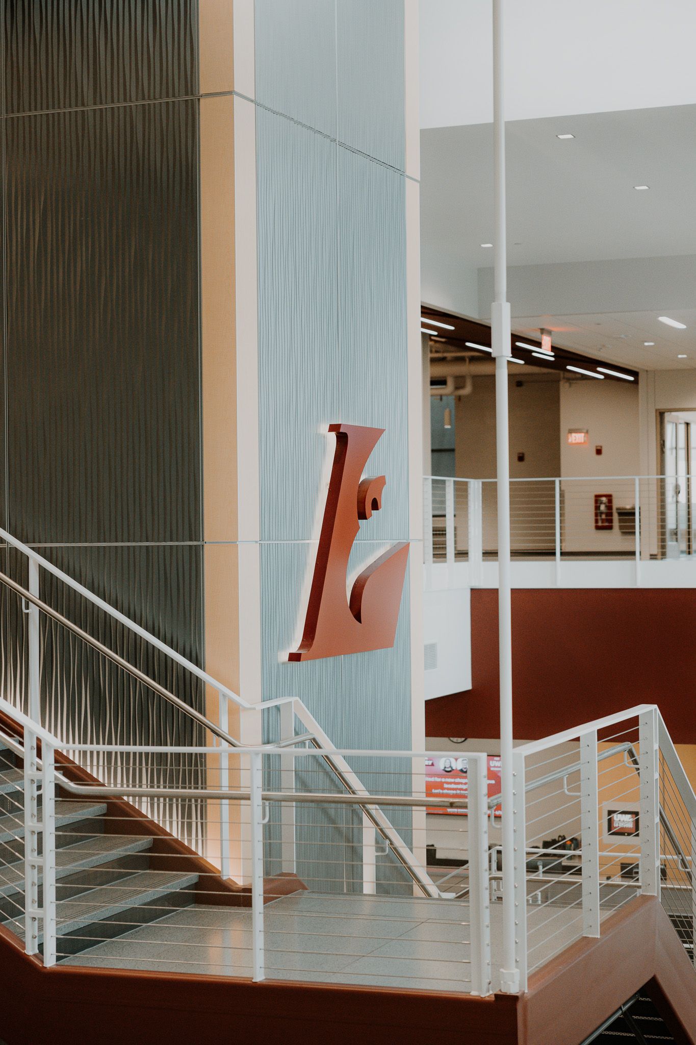 Modern interior hallway with white railings and geometric red wall elements creating a striking architectural design.
