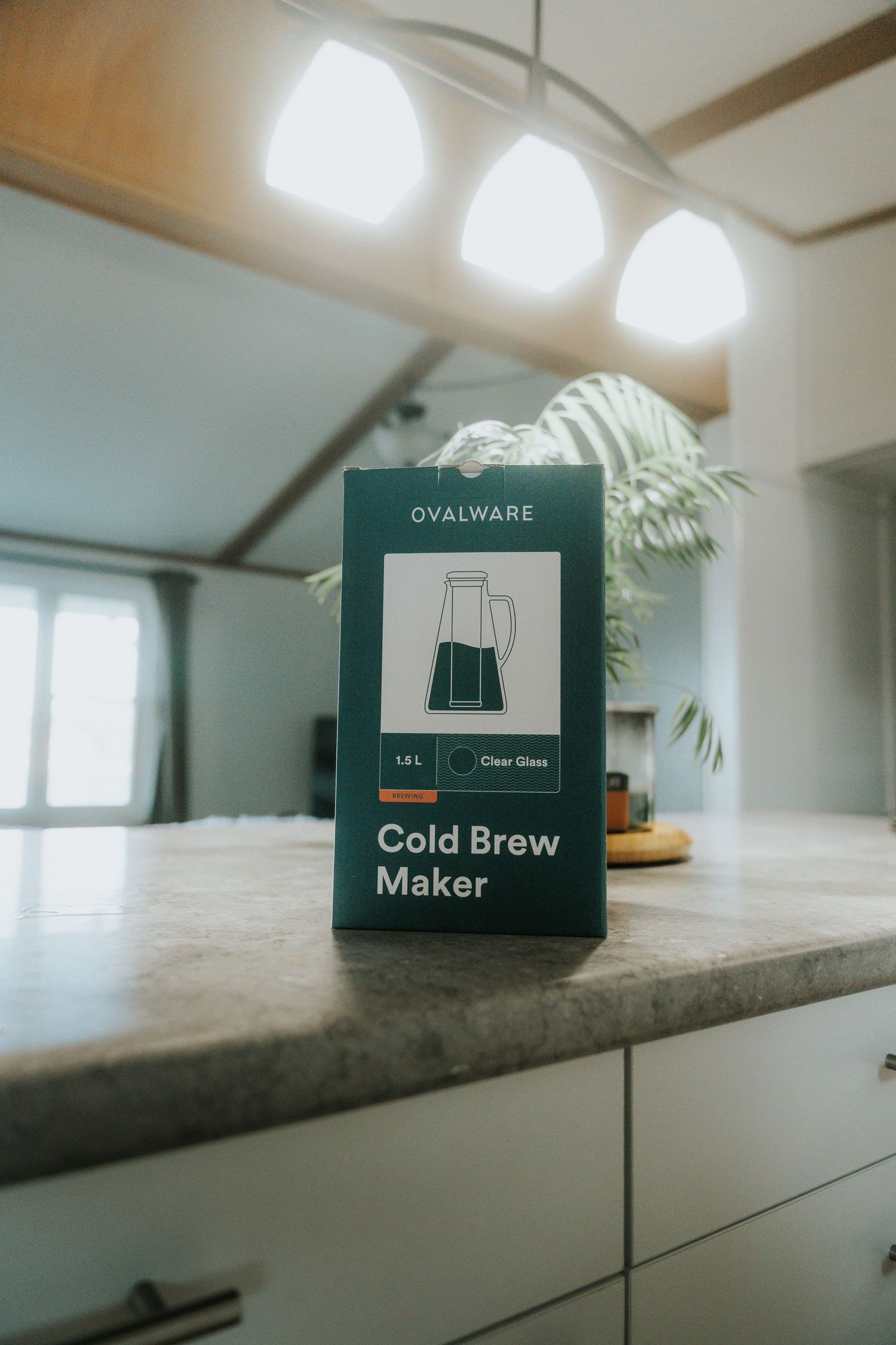 A series of minimalist product packaging boxes for cold brew coffee makers displayed on a light-colored countertop.